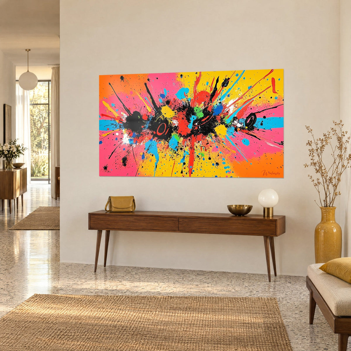 Cuadro con explosión de pintura roja, azul cielo y negra sobre fondo amarillo, colgado encima de una consola de madera, vista de tres cuartos