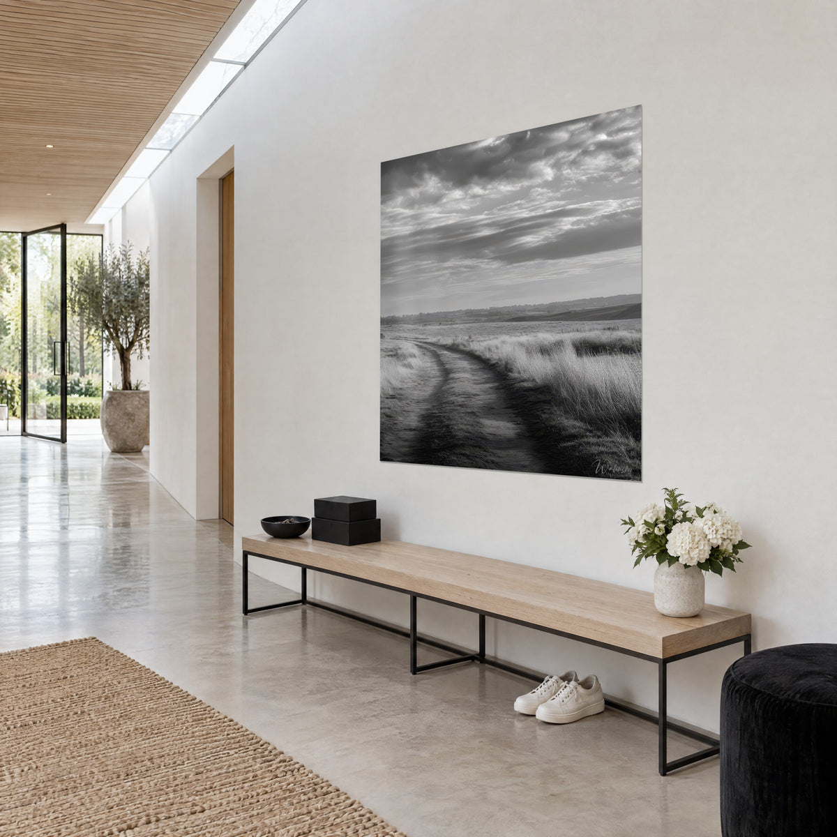 Wall art Rutted country track through a silvery marsh, deep black and pearl grey, hung above a wooden bench