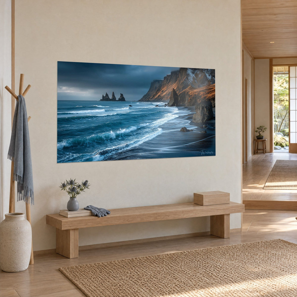 Tableau plage de sable noir léchée d'écume blanche, ciel gris orageux, accroché dans un intérieur japandi en bois clair