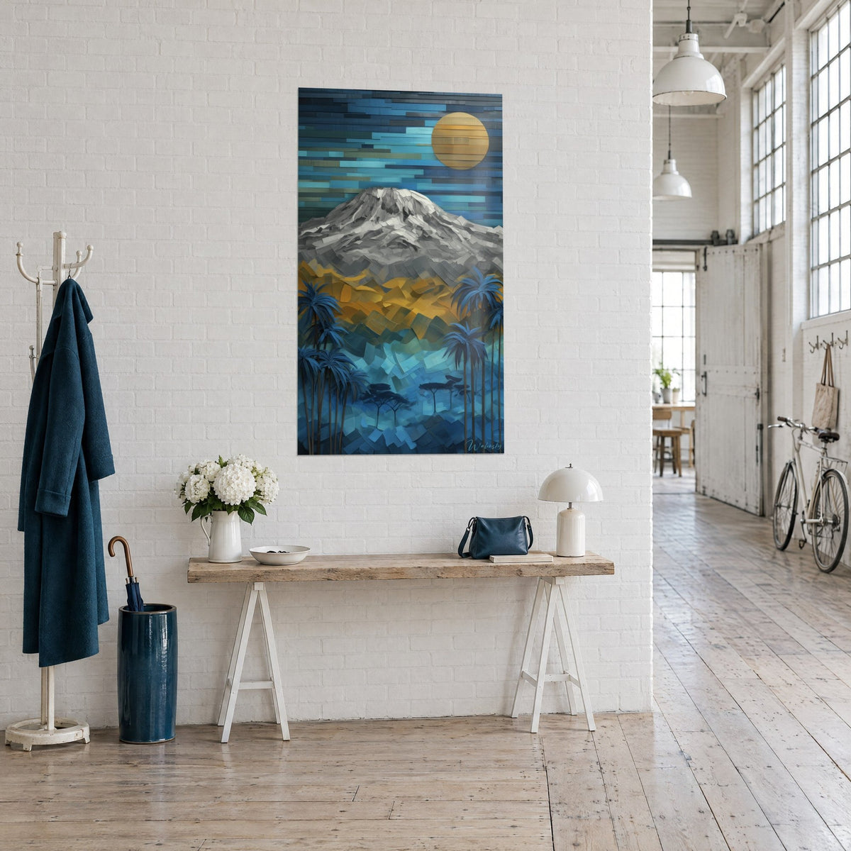 Quadro Vulcano grigio dai frammenti di carta ritagliata, cielo turchese e luna gialla, visto di tre quarti vicino a una consolle in legno