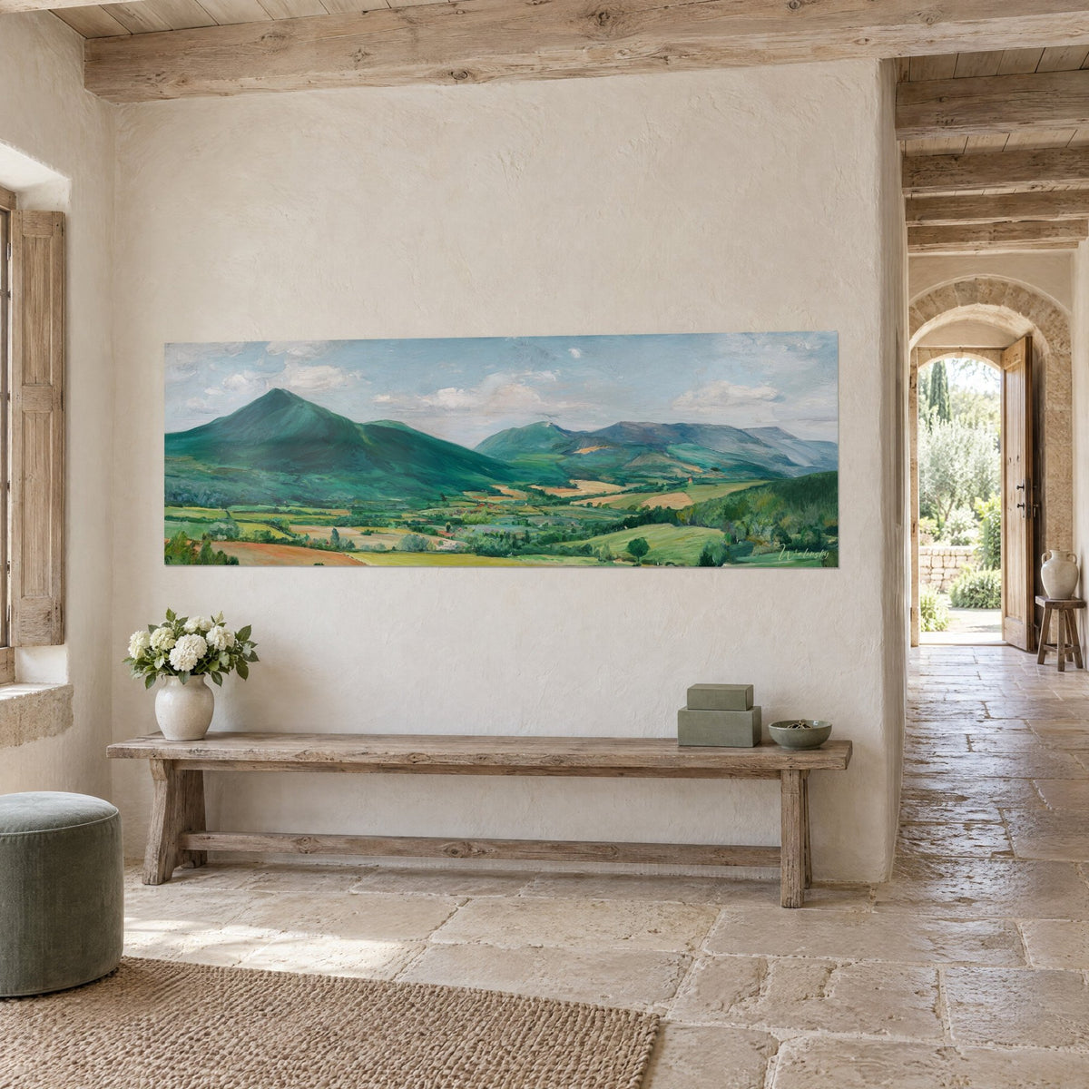 Wall art panoramic view of bluish hills and soft green meadows under white clouds, seen at a three-quarter angle in a stone house