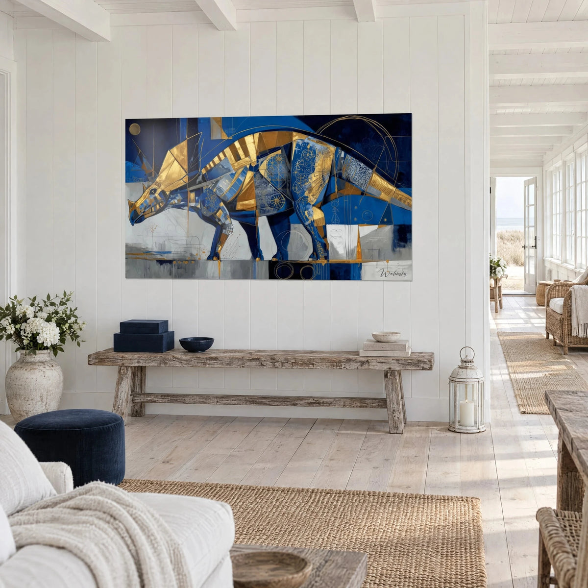 Tableau dinosaure à cornes en aplats bleu roi et or, fond gris perle, vu de trois-quarts sur un mur lambrissé de maison côtière
