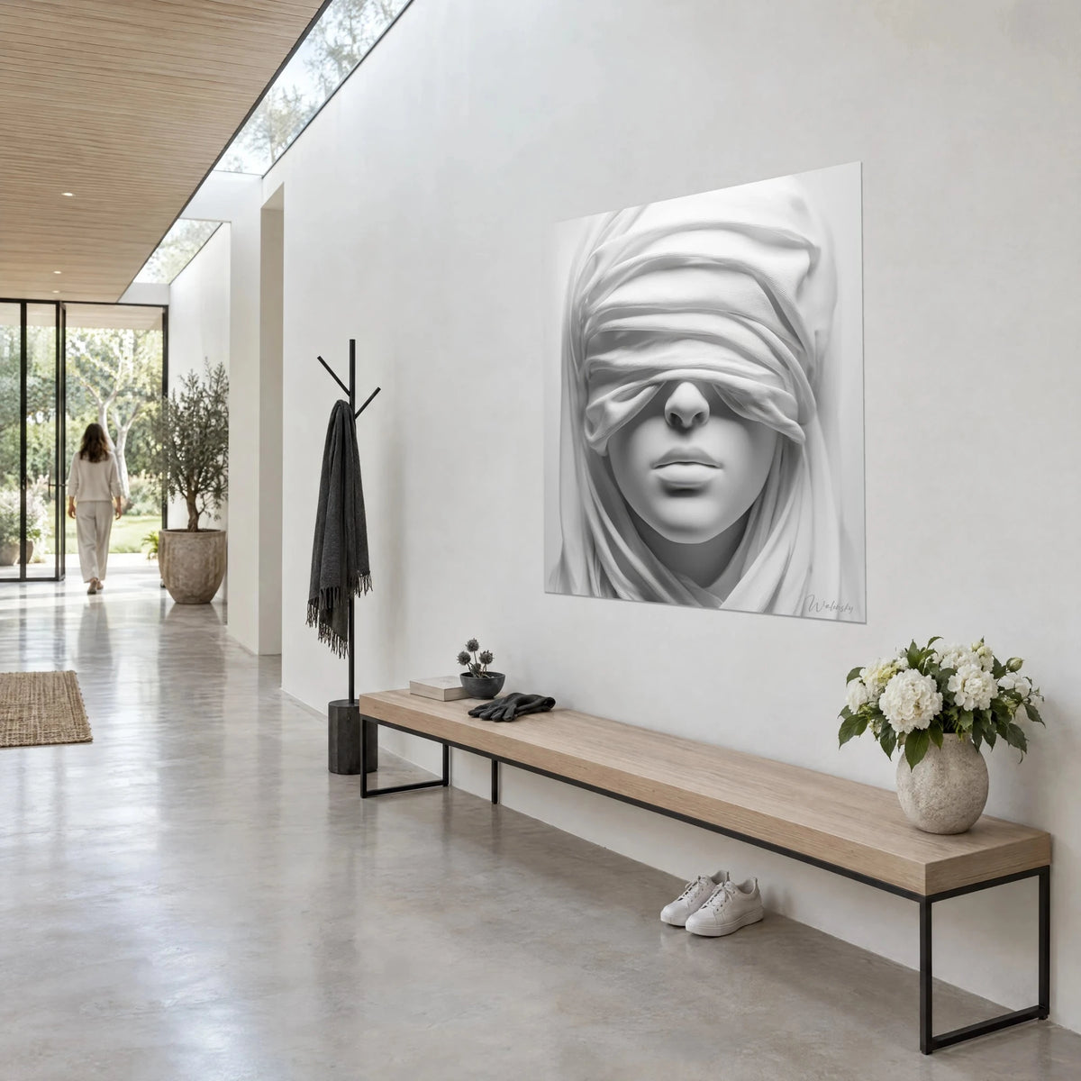 Wall art of a bust draped in ivory fabric, nose and lips in soft grey, white wall, wooden bench, bright glazed corridor