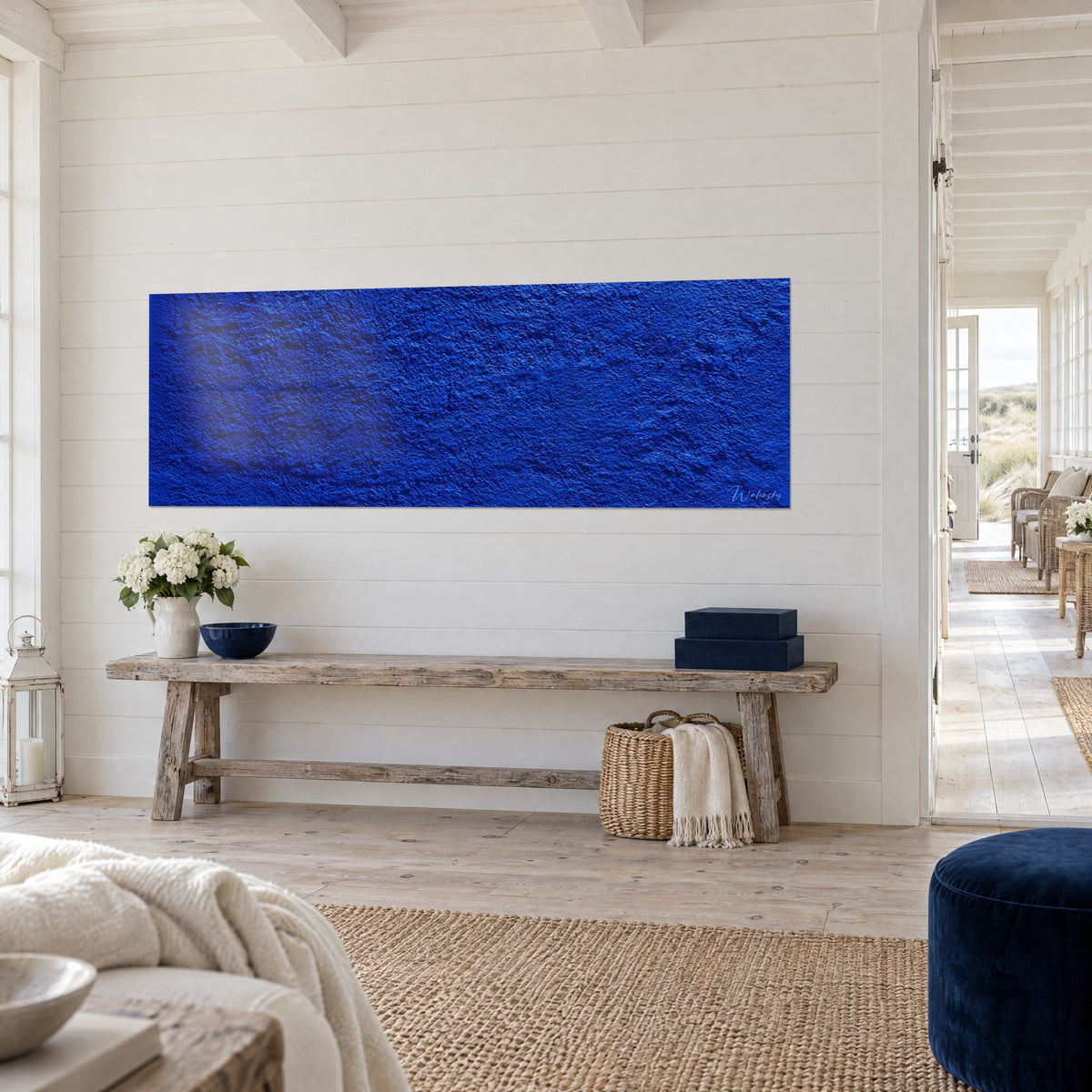Tableau panorama de plâtre bleu roi aux creux sombres, reflets indigo, sur cloison blanche, vue de trois-quarts, maison de bord de mer