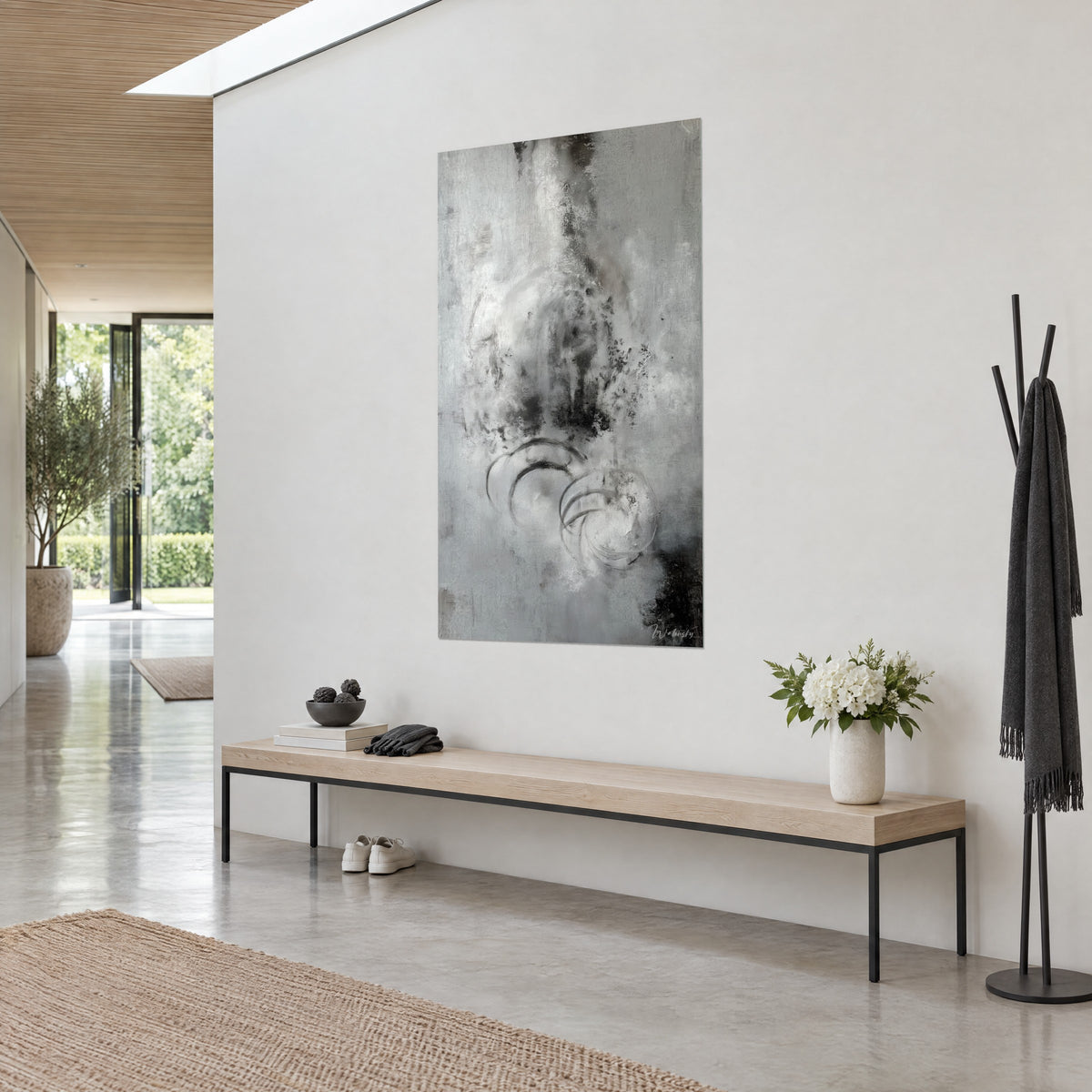 Quadro nuvola di grigio fumo striata di nero, spirali sfumate, vista di tre quarti su parete bianca, ingresso e panca in legno chiaro