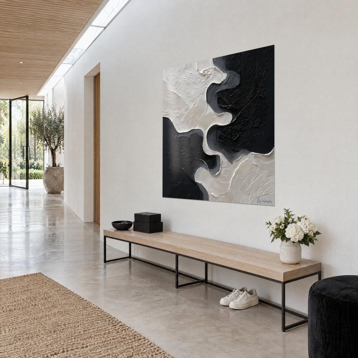 Wall art with billowing cream paint against charcoal blocks of colour, sinuous streaks on a white wall, hallway with a light wood bench