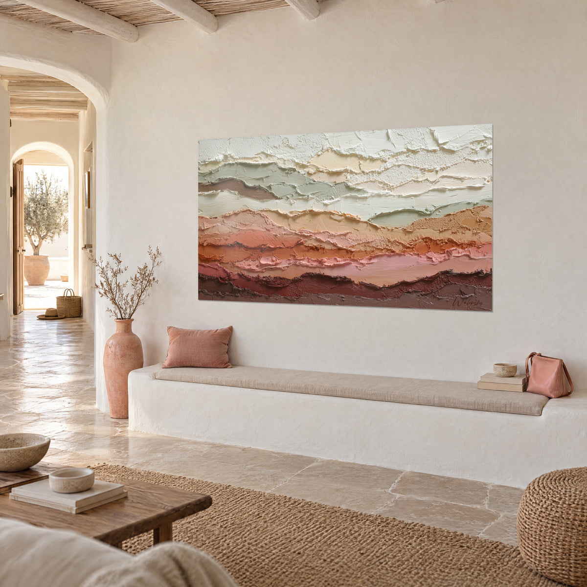 Quadro con rilievi minerali sovrapposti in crema e terracotta, accanto a una panca bianca in una casa mediterranea