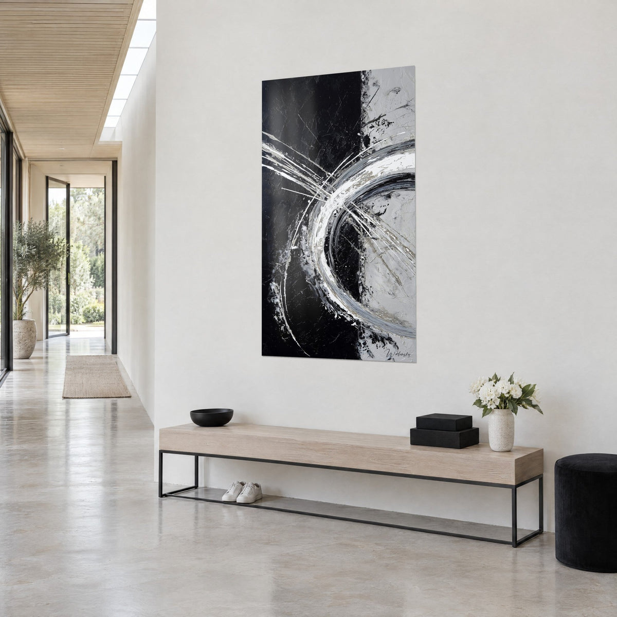 Quadro con arabesco metallico a spirale, nero profondo a sinistra, grigio perla a destra, visto di scorcio sopra una panca in legno