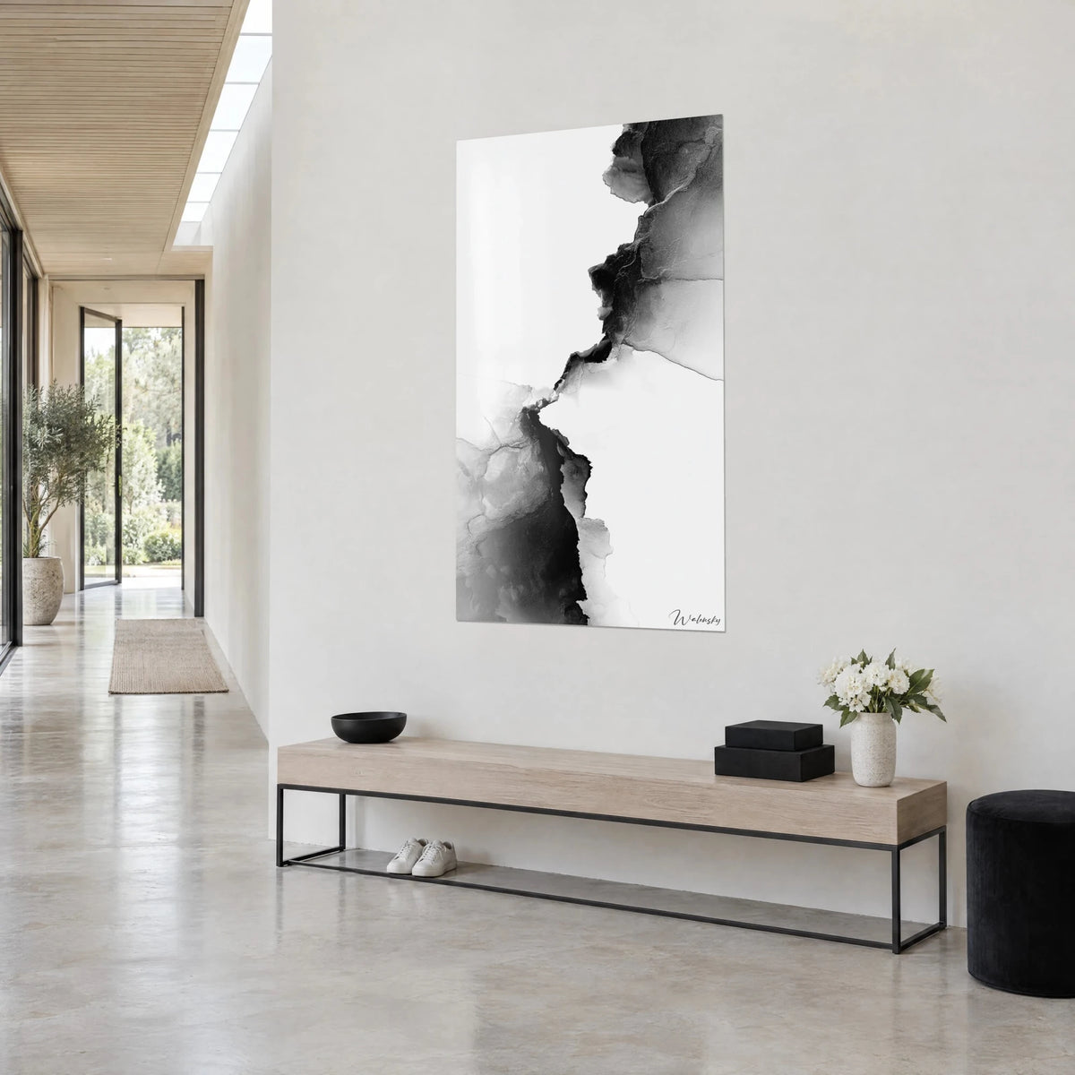 Tableau faille minérale en lavis noir et gris perle, vu de trois-quarts sur un mur blanc, couloir et banc en bois clair