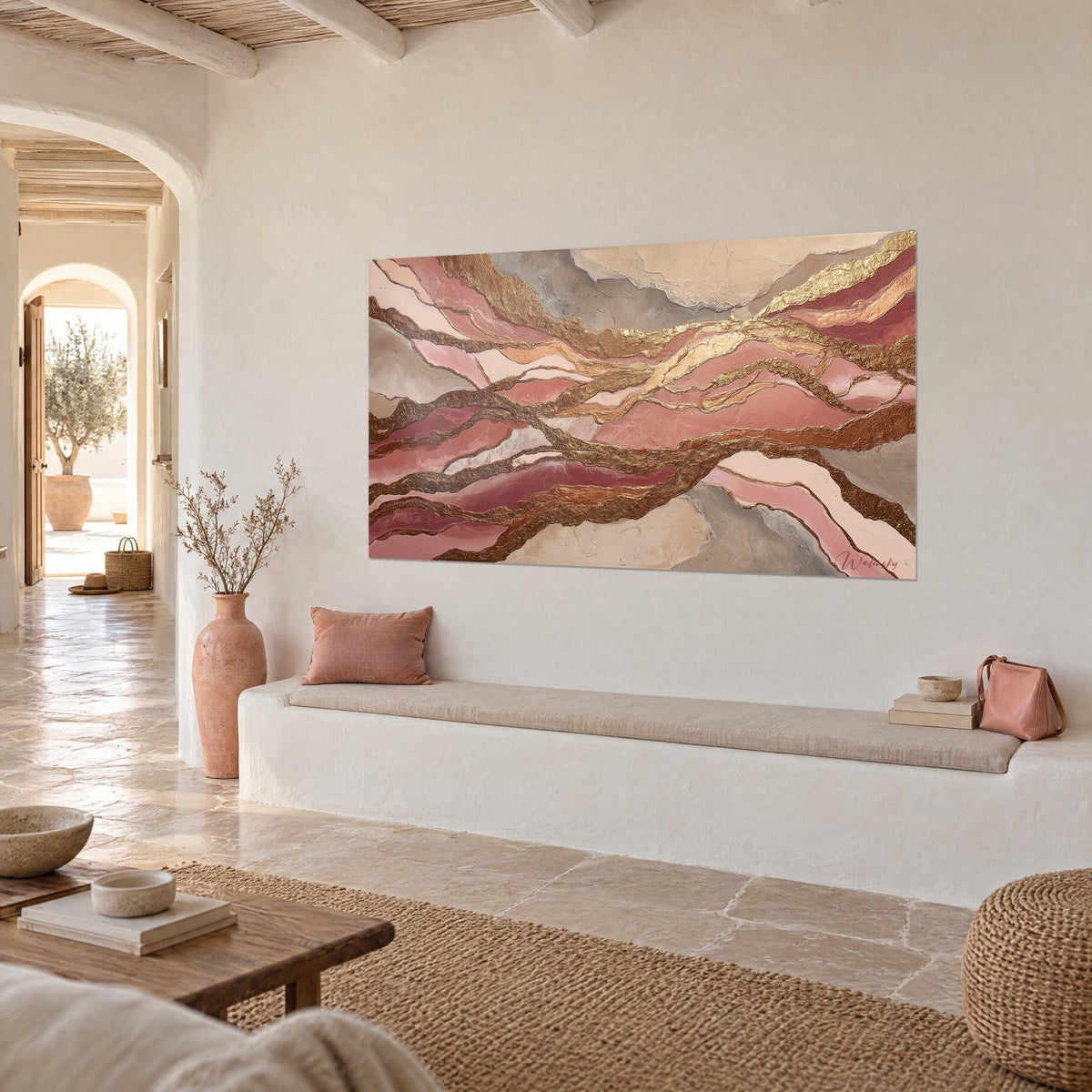 Cuadro con capas rosa coral y oro martillado, visto en tres cuartos sobre una pared crema, encima de un banco blanco