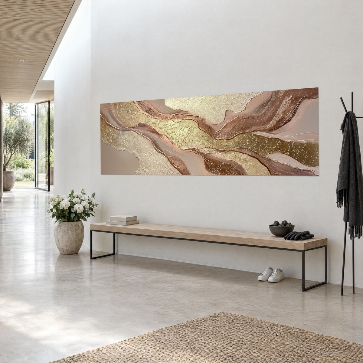 Quadro con colate madreperlate color crema e bronzo satinato, texture screpolata, appeso sopra una panca in legno in un ingresso luminoso