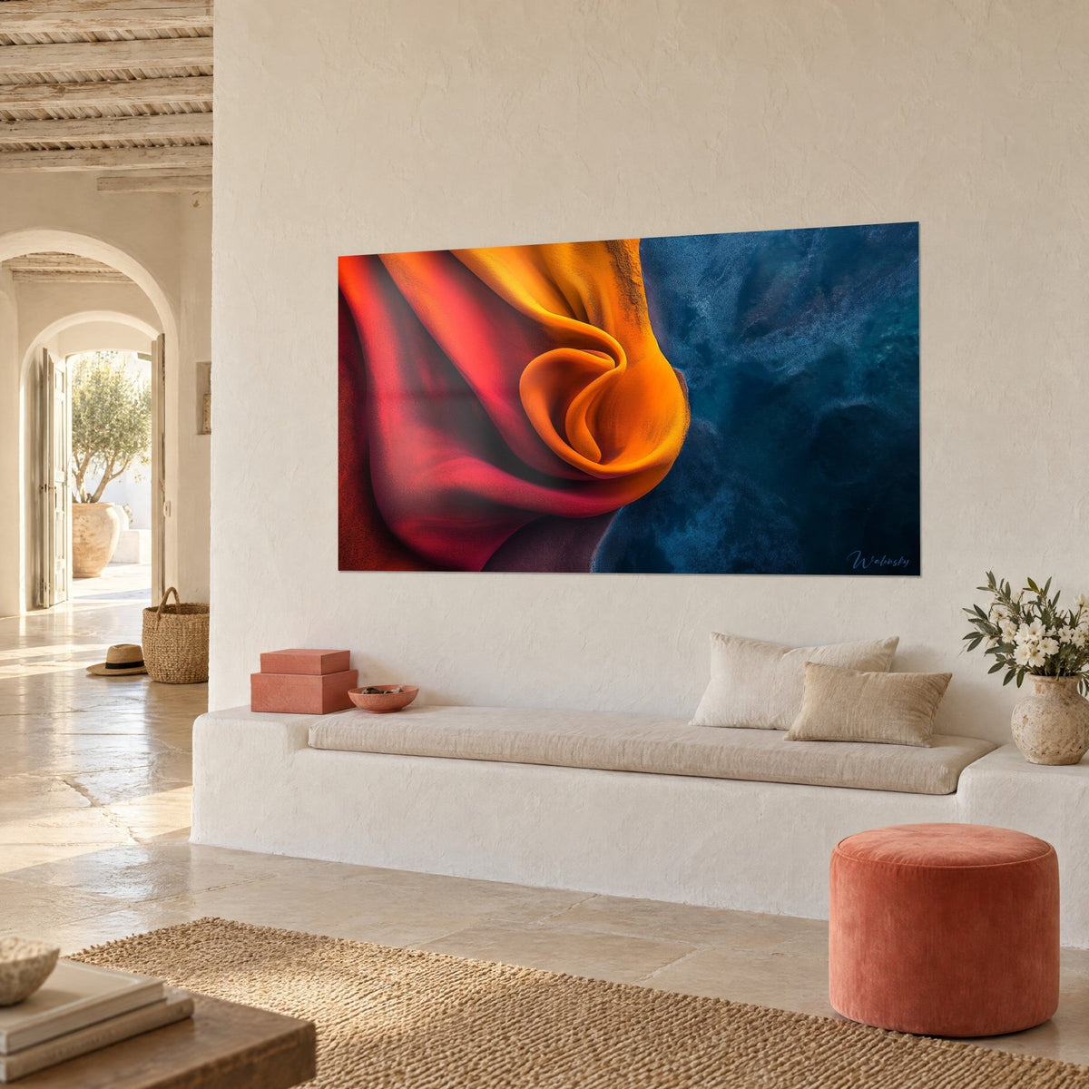 Tableau étoffe en spirale safran contre un bleu marine granuleux, vue de trois quarts près d'une banquette blanche et d'un pouf corail