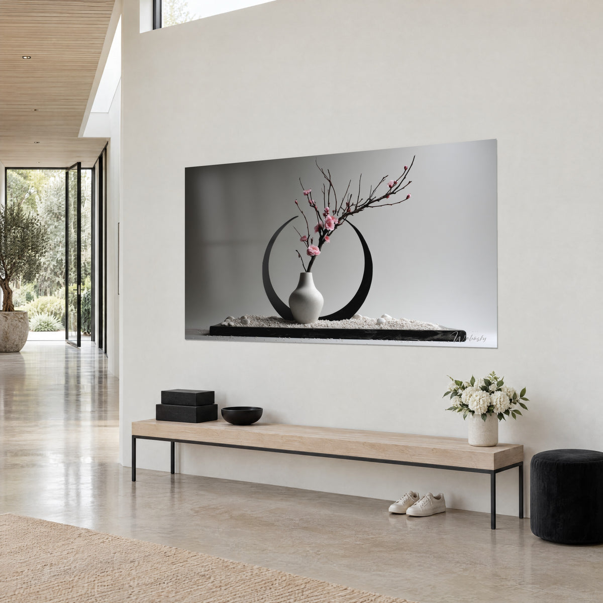 Schilderij minimalistische ikebana-compositie: roze bloeiende tak, open zwarte cirkel en witte kiezelstenen, boven een bank van licht hout