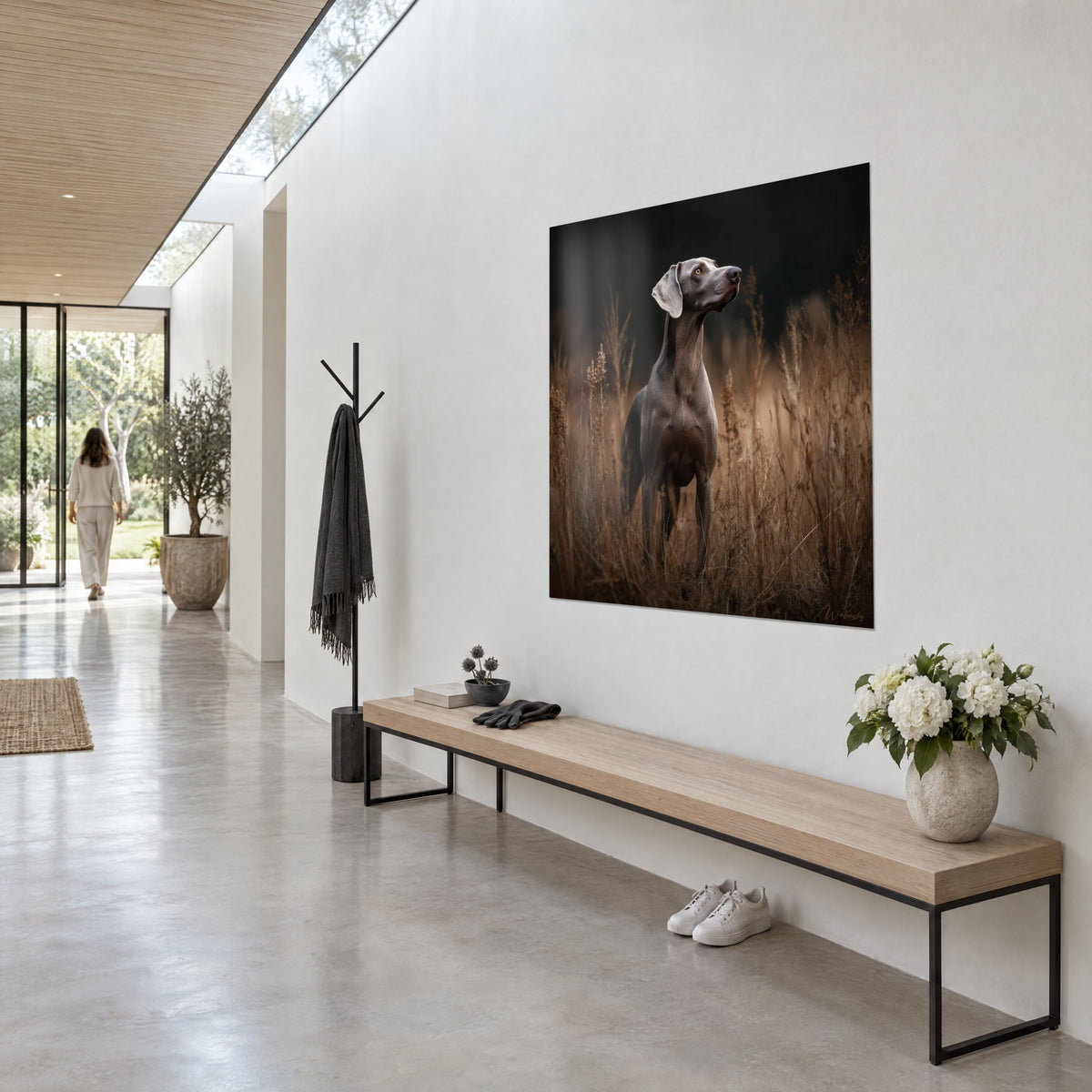 Gemälde aufrecht stehender Weimaraner, erhobene Schnauze, perlgraues Fell auf ockerfarbenem hohen Gras, weiße Wand und Holzbank in einem Flur