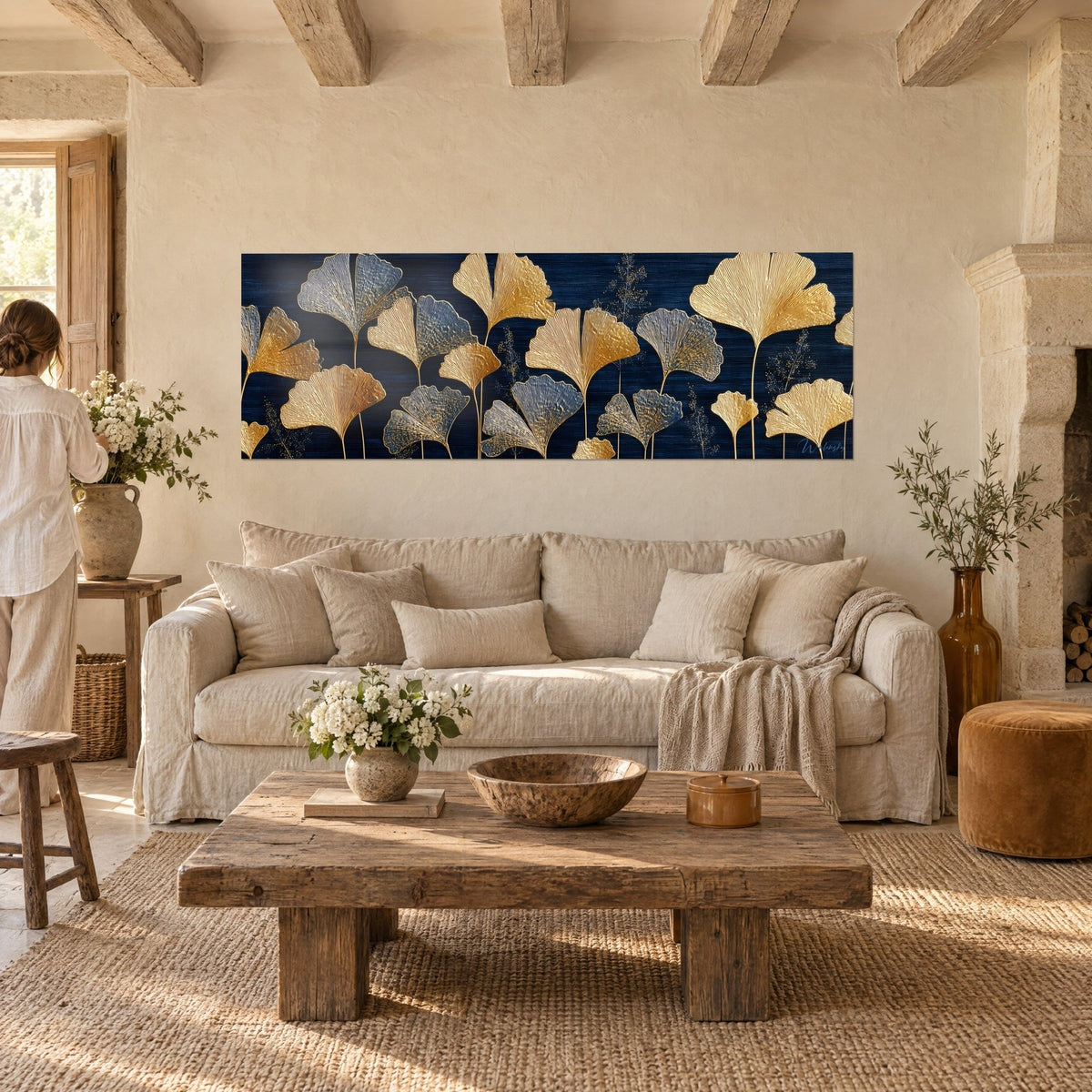 Wall art with golden ginkgo leaves on a navy blue background, ribbed fan-shaped leaves, hanging above a sofa in a bright living room