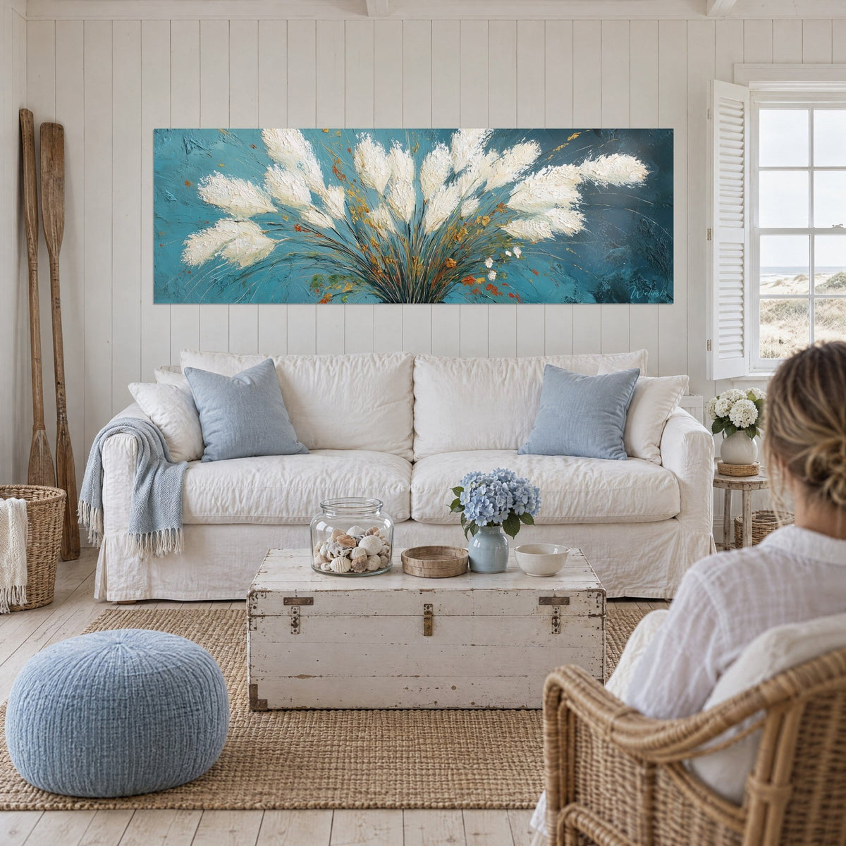 Wall art ivory feather plume bunch on teal blue background, orange accents, above a sofa in a bright living room