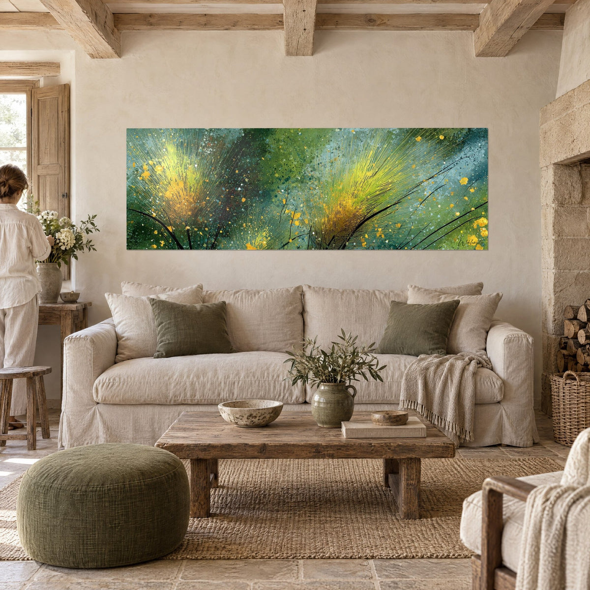 Wall art with golden grass sheaves on a turquoise and green background, person seen from behind, above a sofa in a bright living room