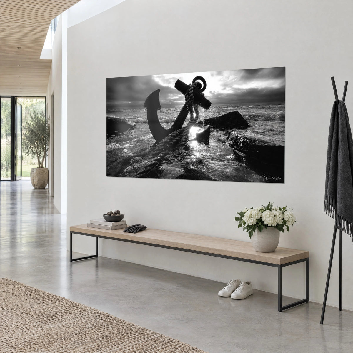 Schilderij Oud scheepsanker op donkere rotsen, stormachtige grijze lucht en een witte zonnestraal, driekwart zicht op een lichte muur