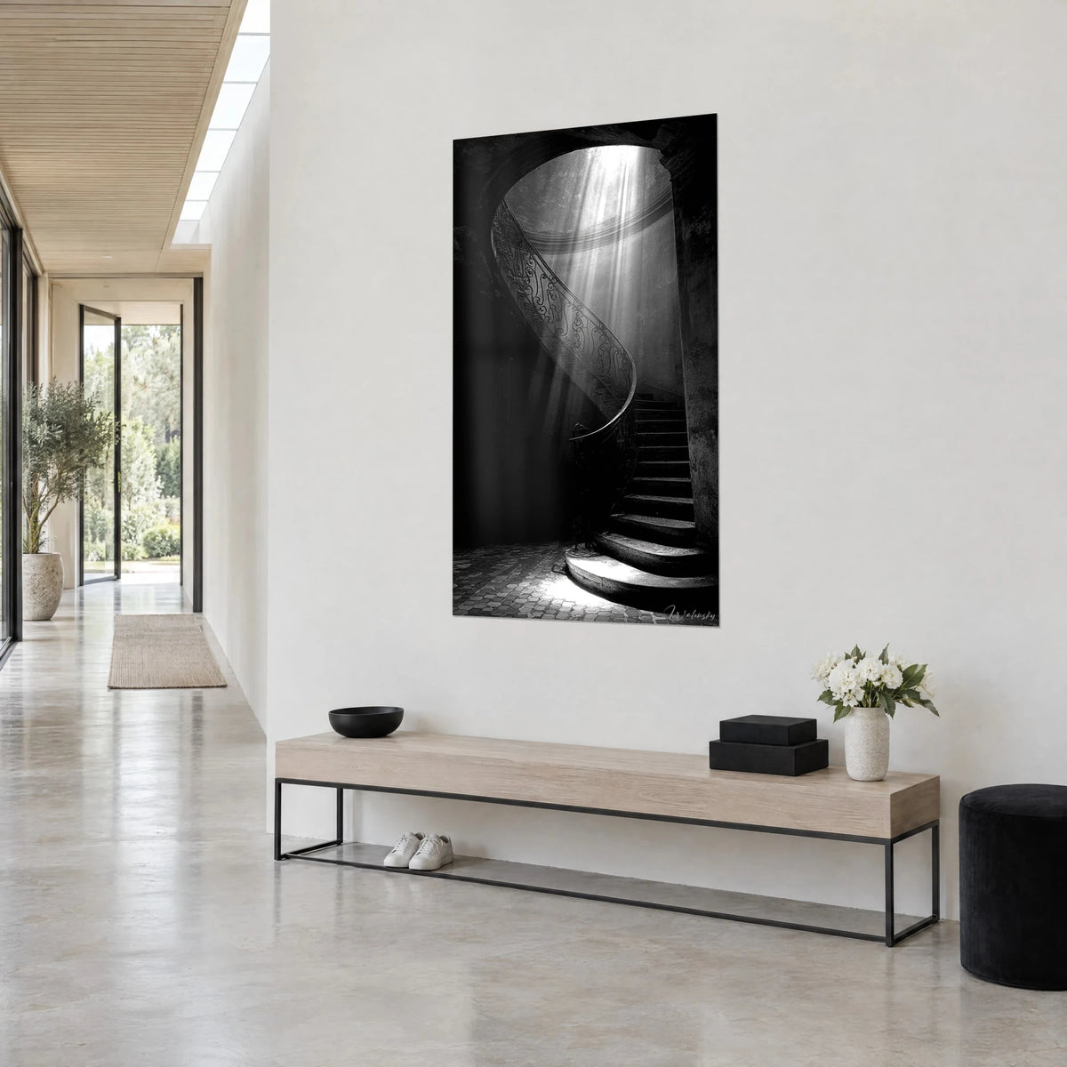 Wall art spiral of stone steps under a white skylight, deep black shadows, on a light wall in a hallway