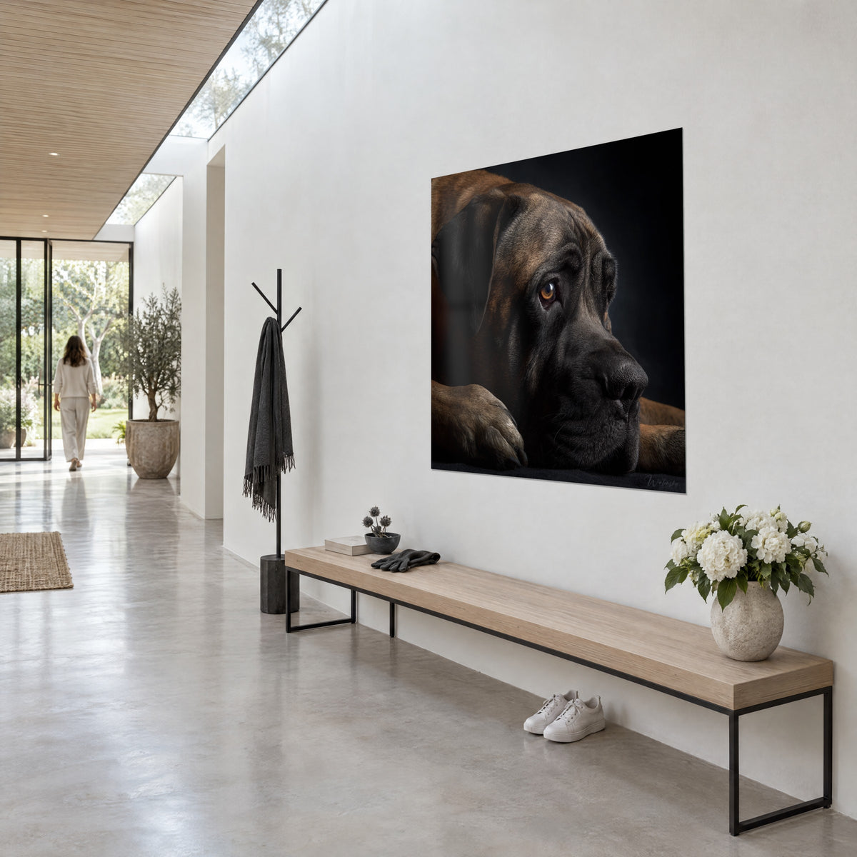 Schilderij liggende mastiff, poot onder de wang gevouwen, brons en diep zwart, opgehangen aan de muur van een lichte hal