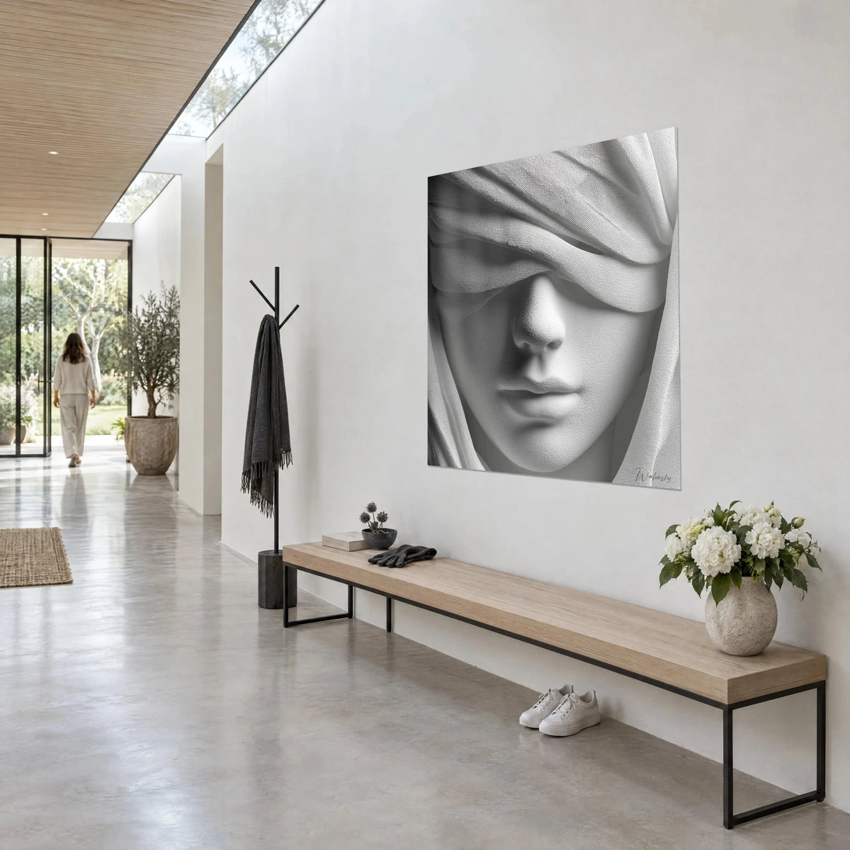 Quadro ritratto con fascia di tessuto bianco plissettato, bocca chiusa grigio perla, parete chiara sopra una panca di legno