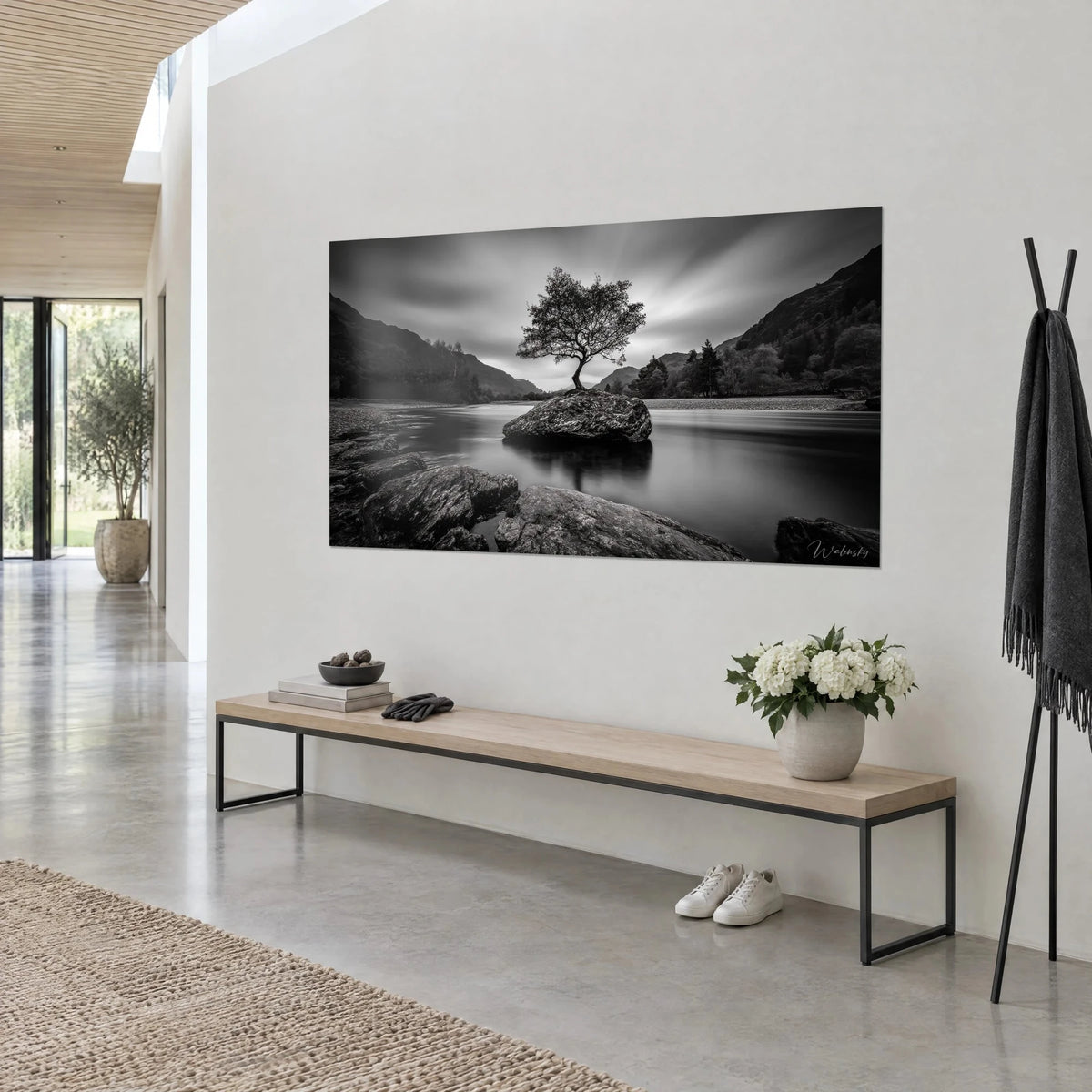 Tableau chêne isolé sur son îlot de pierre, eau lisse gris perle et montagnes sombres, accroché de trois-quarts près d'un banc en bois clair