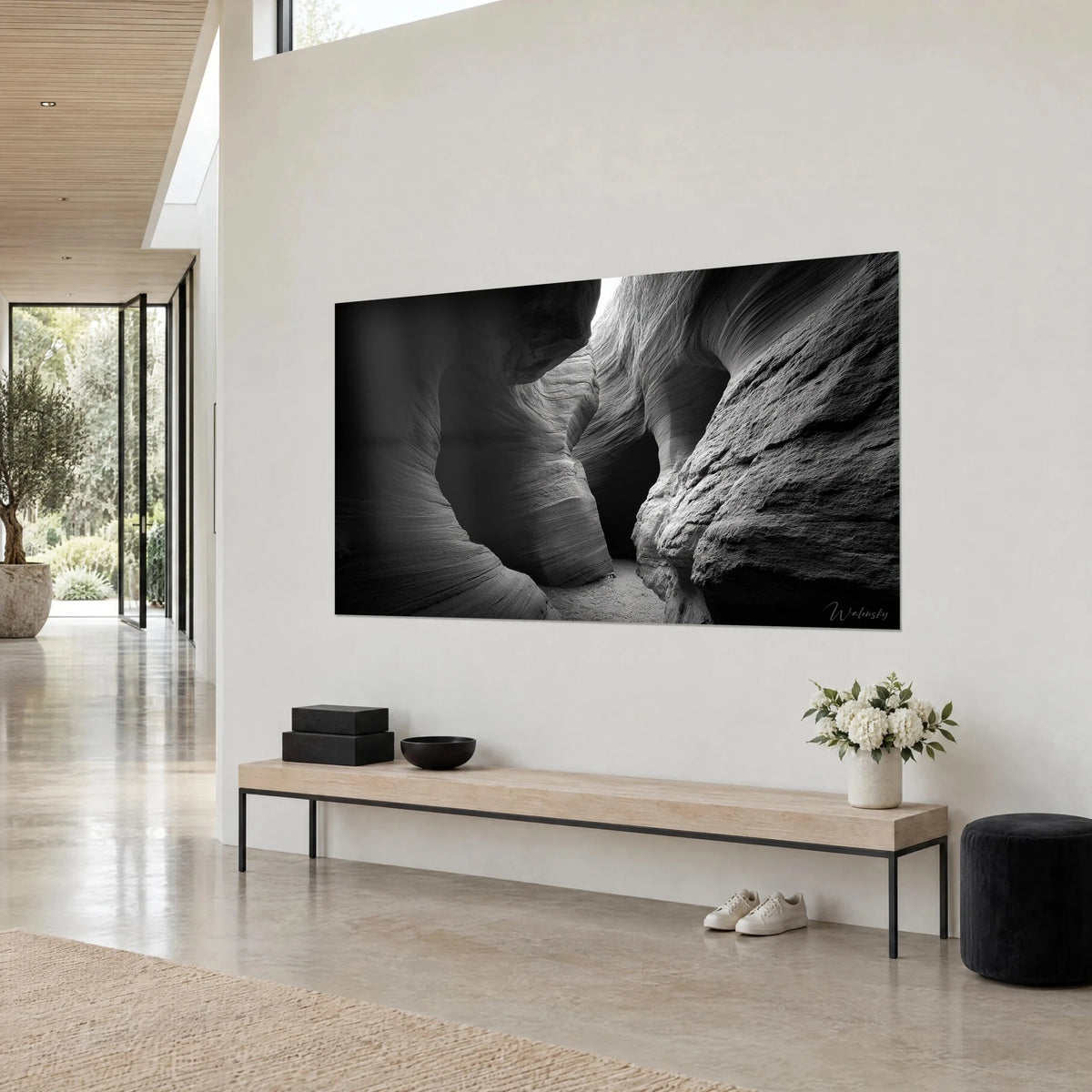 Tableau gorge rocheuse aux ondulations argentées, strates grises et noir profond, mur blanc et banc en bois clair en maison d'architecte