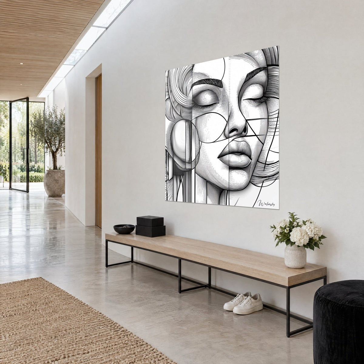 Quadro volto di donna in disegno geometrico, labbra carnose e ciocche nere su fondo bianco, appeso in un corridoio chiaro, vista a tre quarti