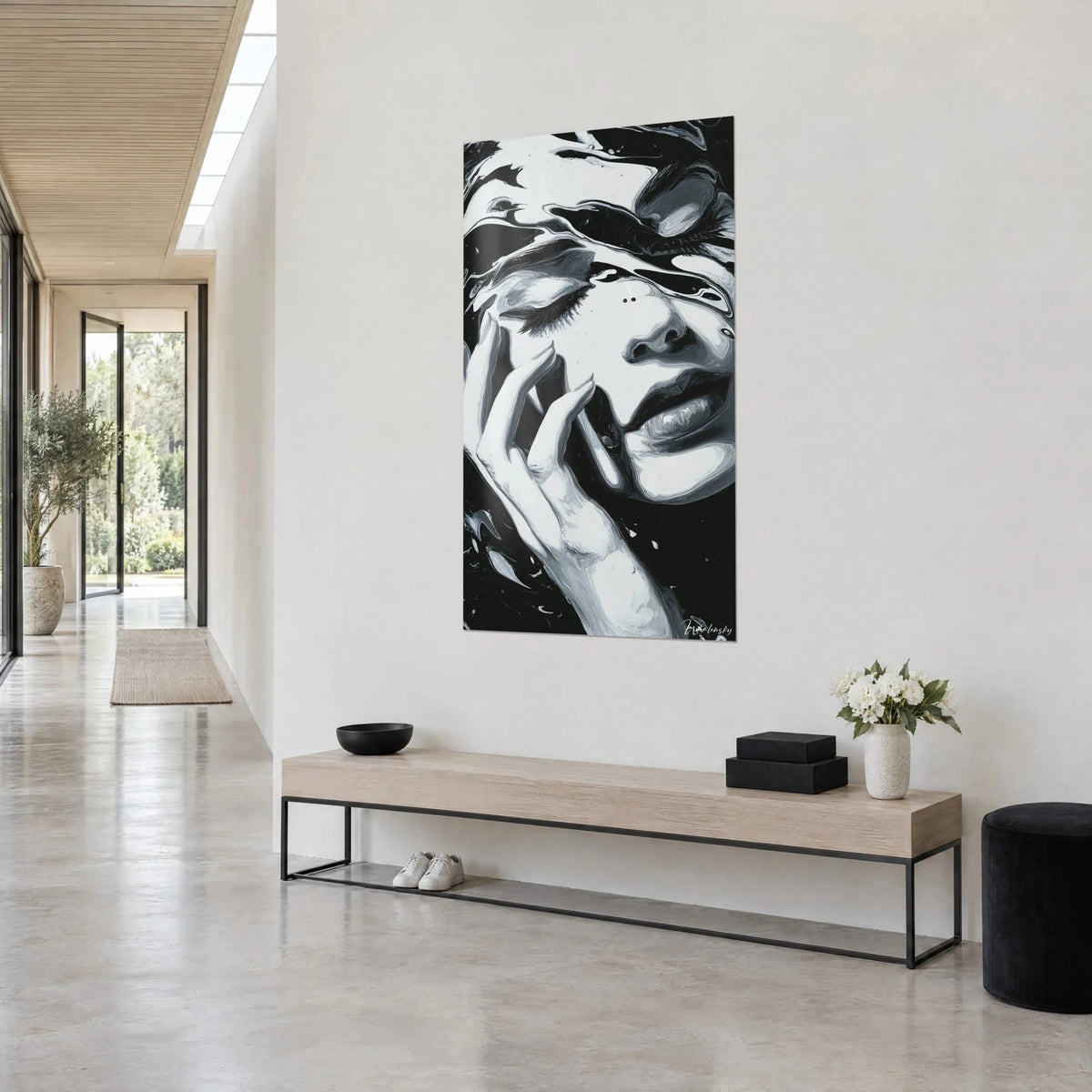Wall art portrait in grey and ivory paint drips, full lips and sculpted nose on a deep black background, bright hallway and low bench
