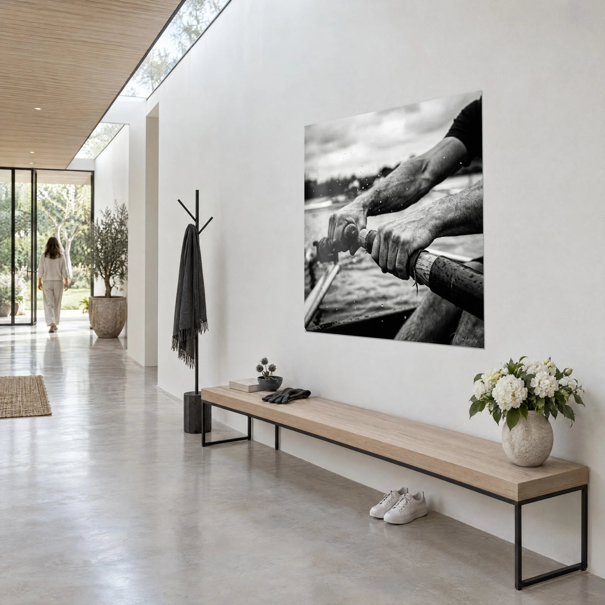 Wall art rower gripping two damp wooden handles, overcast grey sky and dark water, in an architect's hallway