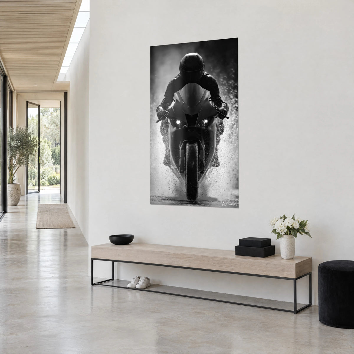 Wall art of a helmeted rider in black leather launching through the rain, bright headlights, pearl grey background, three-quarter view in an architect's hallway
