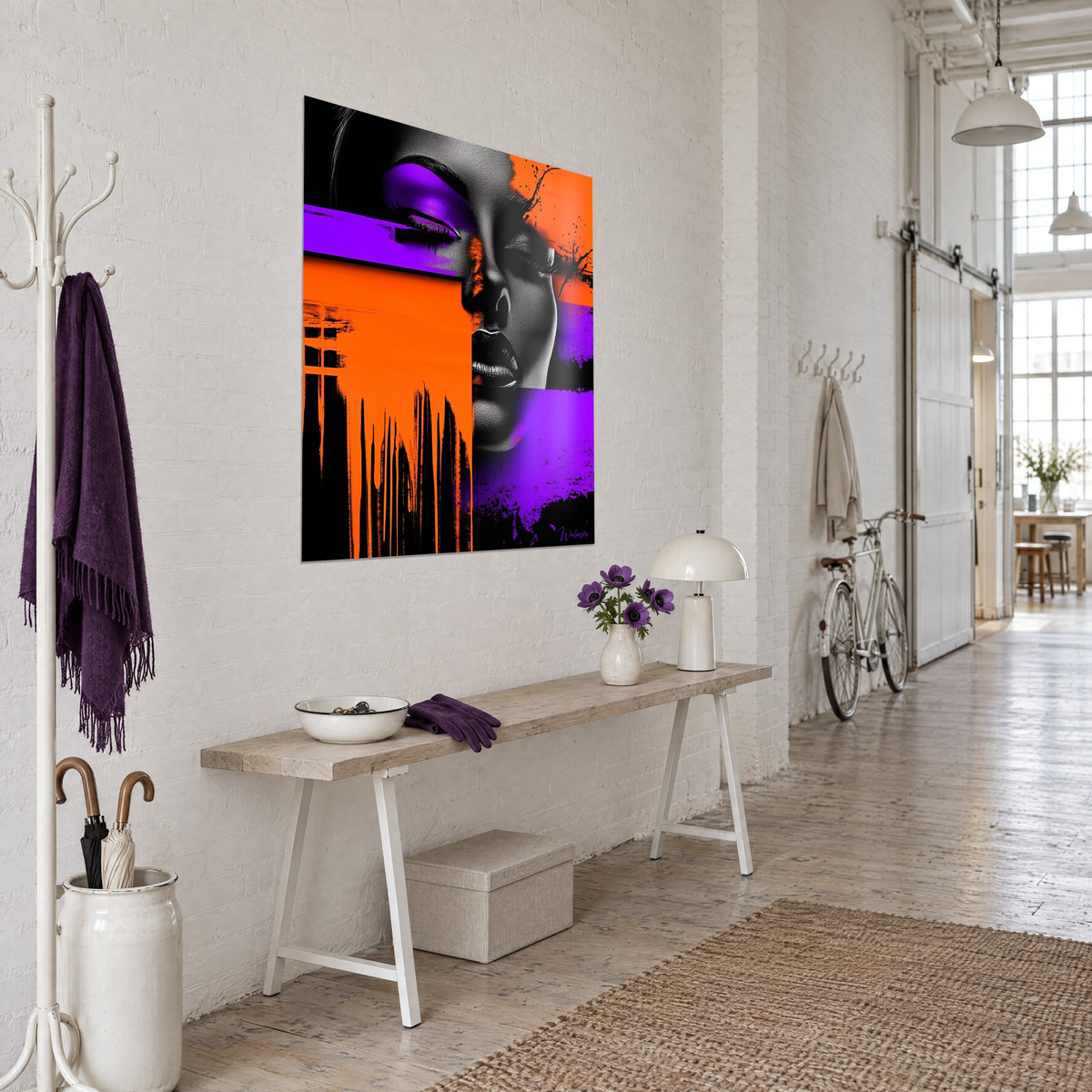Cuadro rostro de mujer en blanco y negro, manchas naranjas vivas y violetas, goteos negros, colgado en una pared blanca de loft