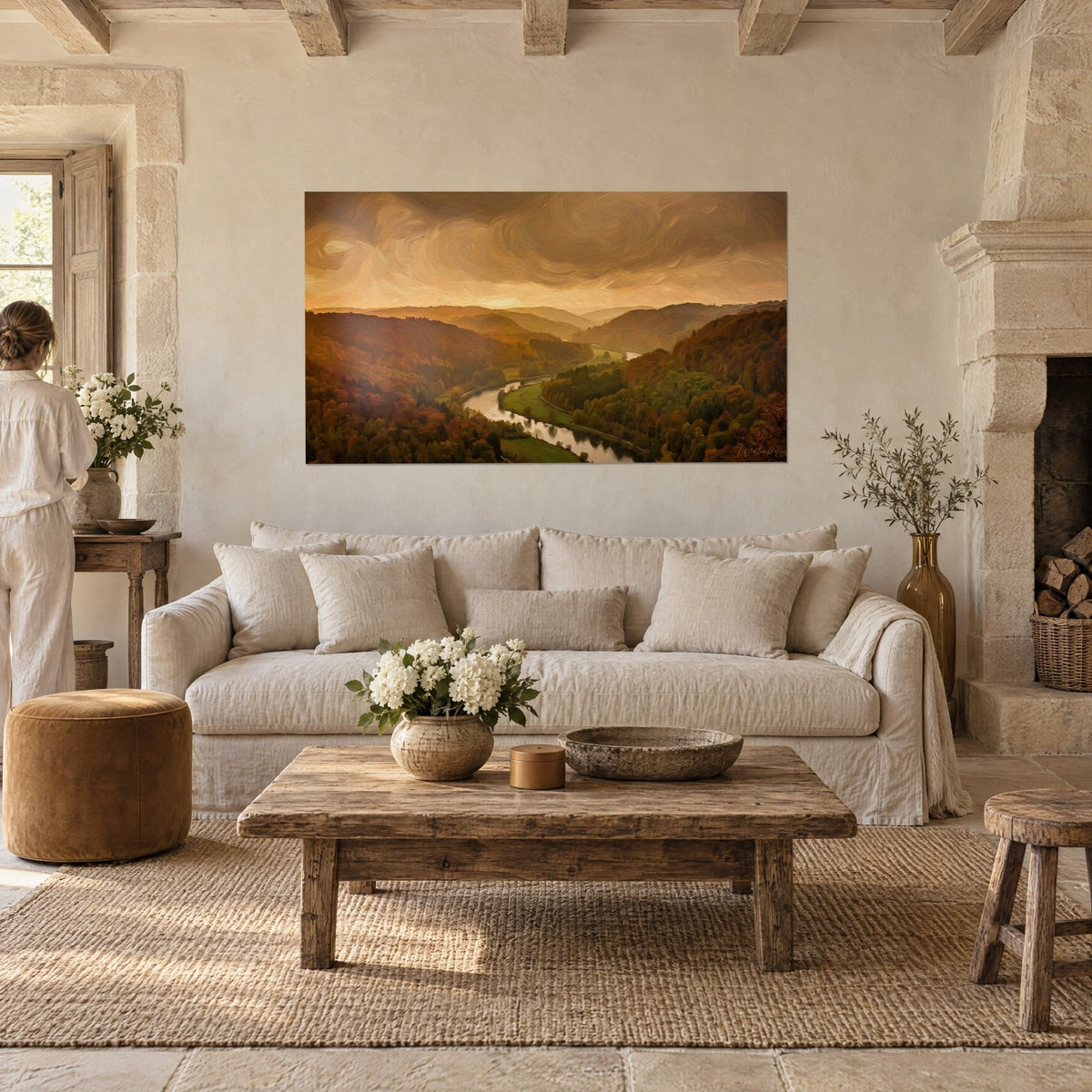 Gemälde einer gewundenen Flusslandschaft unter kupfrigem Himmel, rostrote und grüne Wälder, eine Frau von hinten, über einem Sofa in einem hellen Wohnzimmer