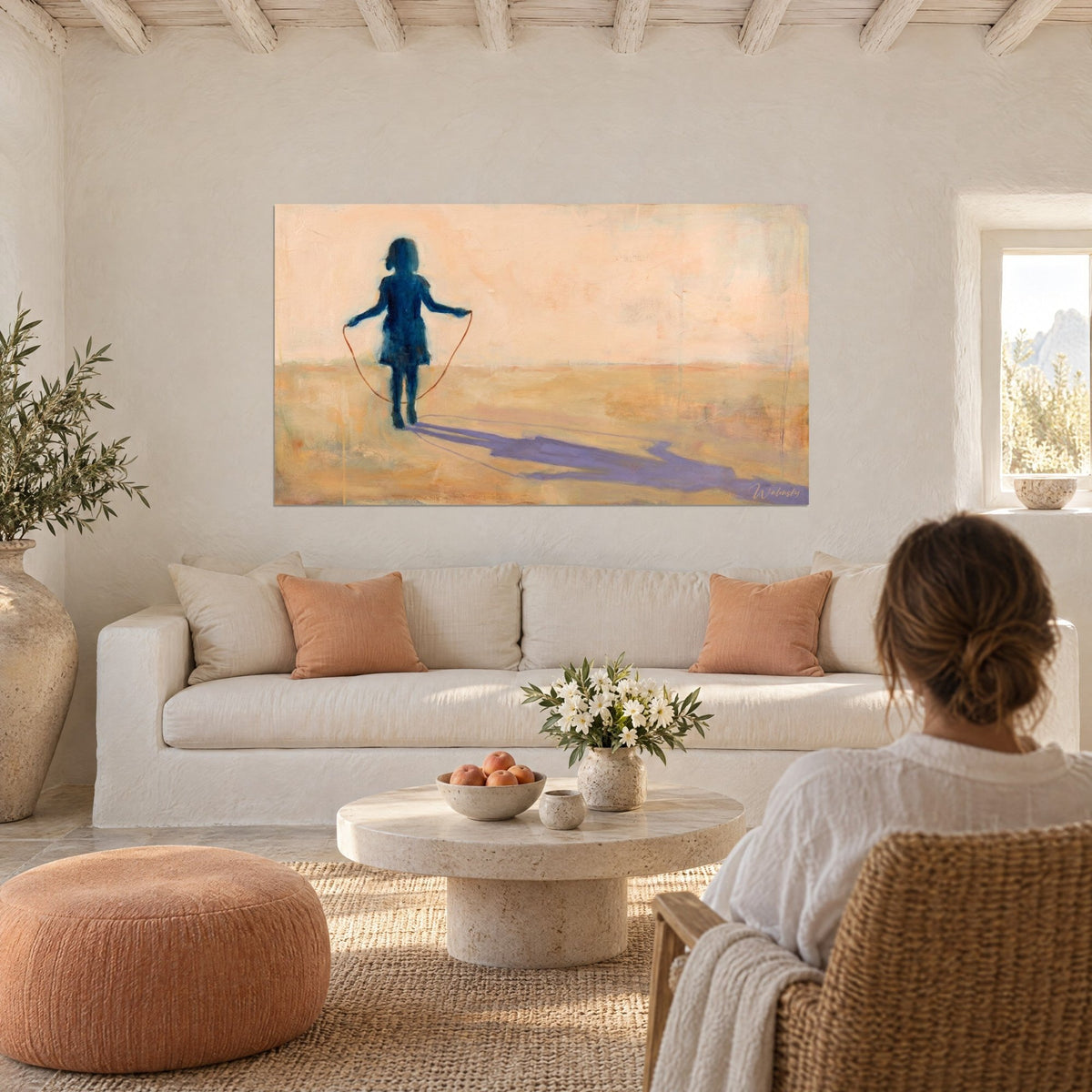 Gemälde Mädchen beim Seilspringen, nachtblaue Silhouette auf pfirsichfarbenem Sand, violetter Schatten, über einem Sofa in einem hellen Wohnzimmer