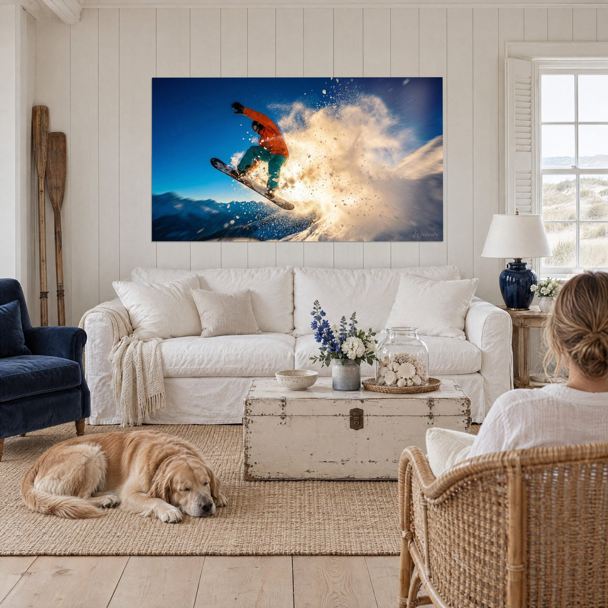 Wall art snowboarder in an orange jacket leaping through a golden cloud of powder snow, blue sky, above a sofa in a bright living room