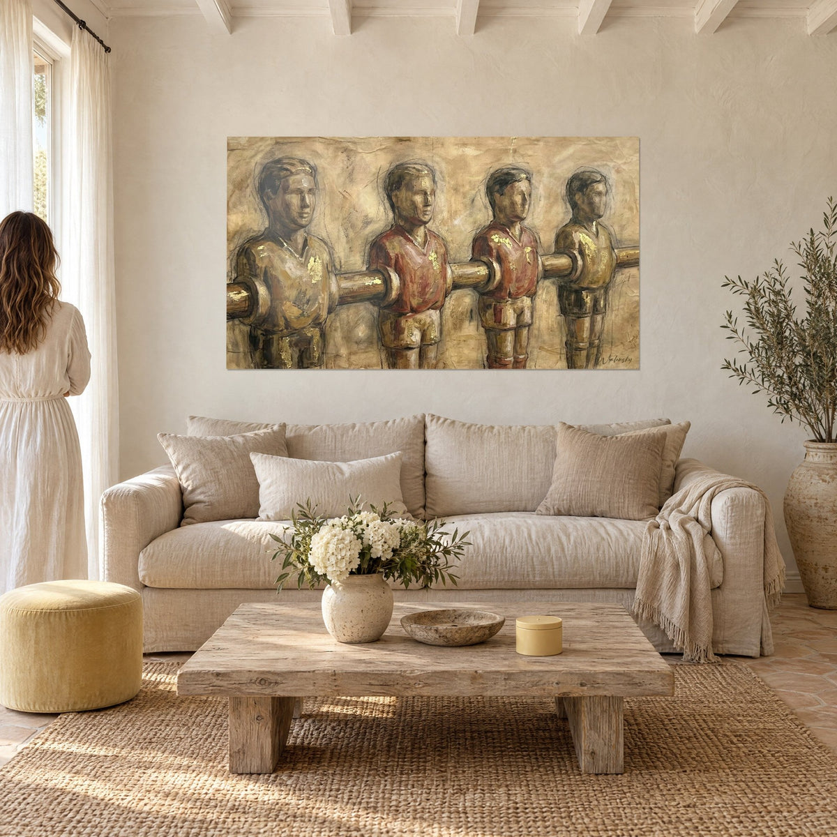Quadro con quattro figurine da calcio balilla allineate, maglie ruggine e oro, sopra un divano in un soggiorno luminoso