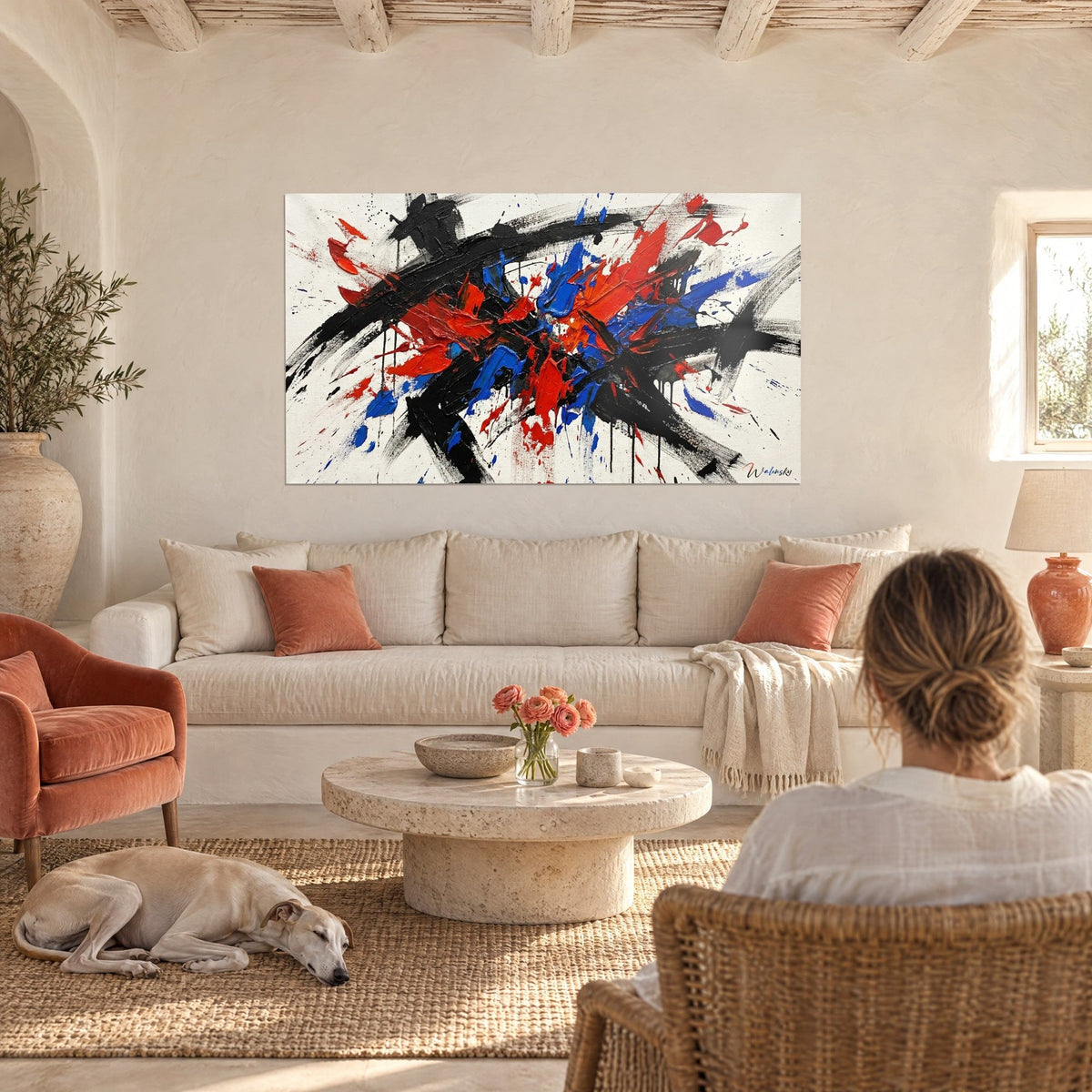 Wall art abstract brilliance in vermilion red and cobalt blue, bold black strokes on cream background, above a sofa in a bright living room