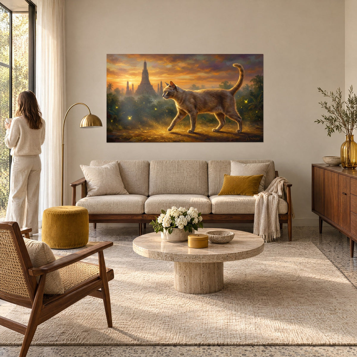 Schilderij zilvergrijze korat-kat die voor een gouden tempel loopt, oranje lucht, vrouw van achteren, boven een bank in een lichte woonkamer