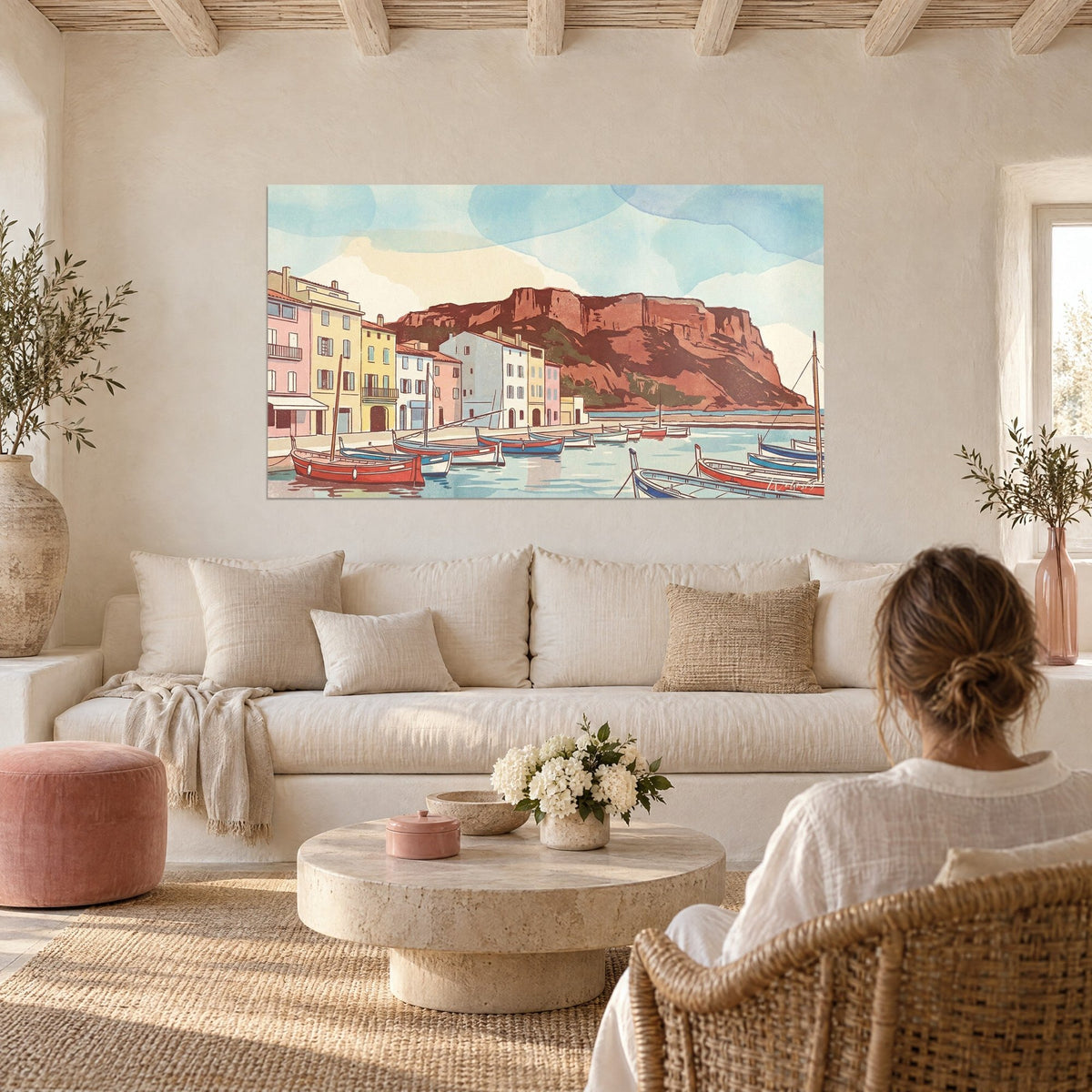 Tableau port provençal aux façades pastel et falaise rouge, pointus rouges au premier plan, au-dessus d'un canapé dans un salon lumineux