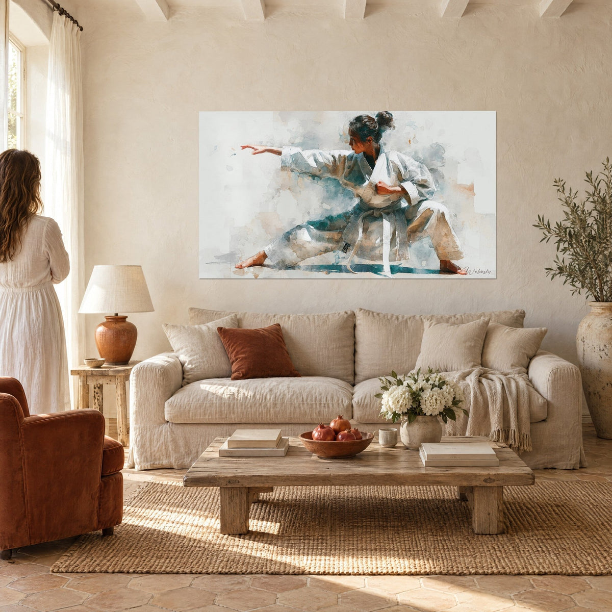 Quadro di una karateka in kimono bianco, gambe divaricate e braccio teso, velatura blu turchese e ocra, sopra un divano in un soggiorno luminoso