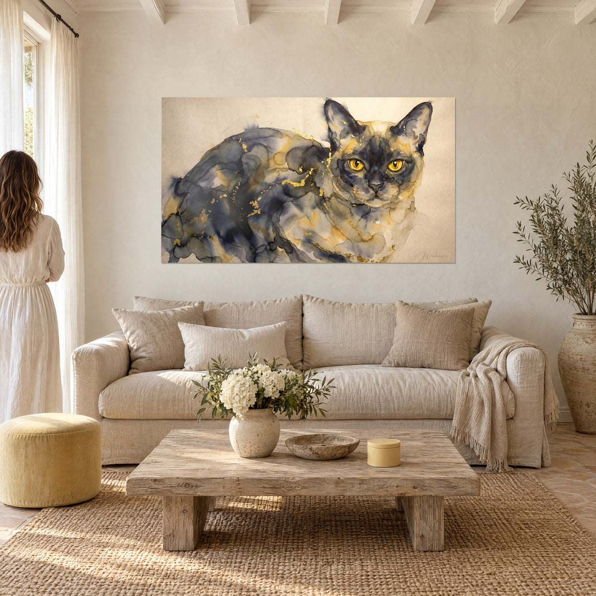 Tableau chat burmese aux yeux ambrés, aquarelle gris ardoise et paillettes d'or, au-dessus d'un canapé dans un salon lumineux