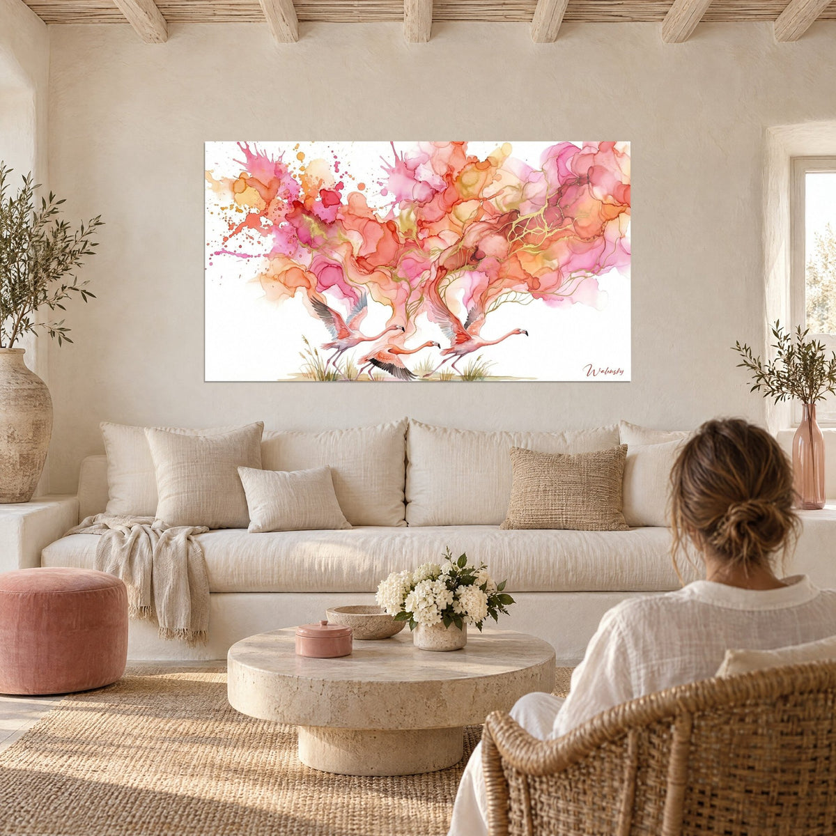 Cuadro flamencos en pleno vuelo, acuarela coral y fucsia veteada de oro, encima de un sofá en un salón luminoso