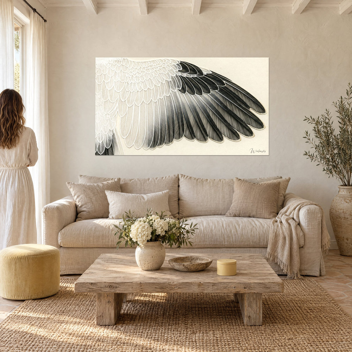 Cuadro ala de cigüeña con plumas marfil y negro azabache, pareja de espaldas, encima de un sofá en un salón luminoso