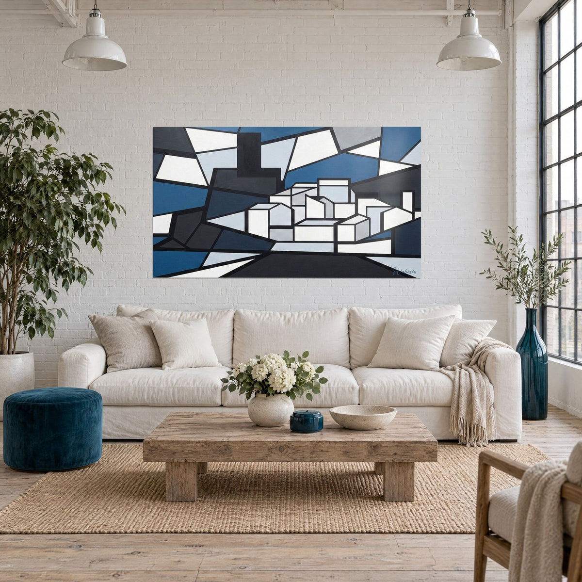 Cuadro pueblo cubista en facetas azul petróleo, blanco y gris pizarra, sobre un sofá en un salón luminoso