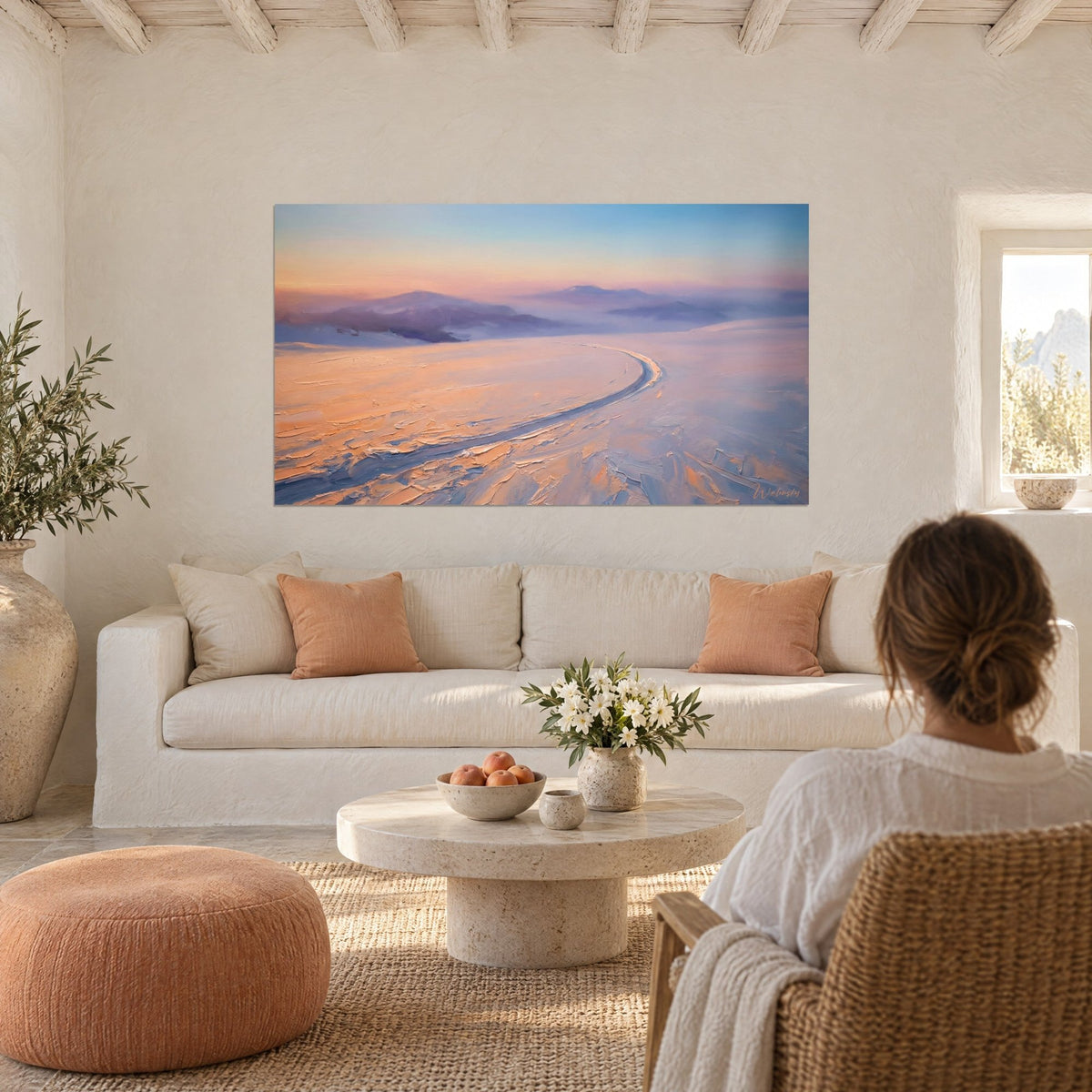 Gemälde verschneite Piste, die sich unter einem pfirsichfarbenen und blauen Himmel krümmt, dicke Ölfarbe, Frau von hinten, über einem Sofa in einem hellen Wohnzimmer