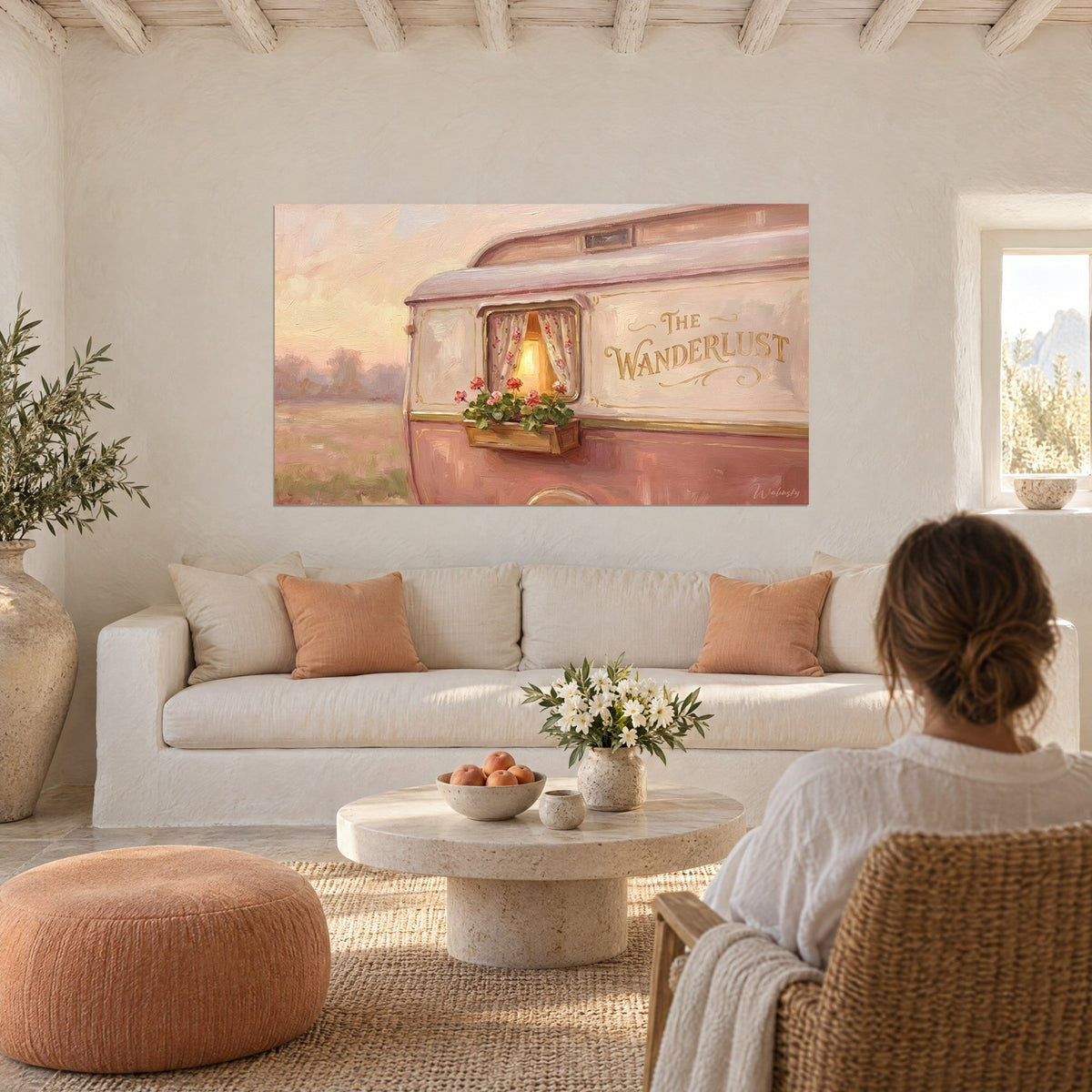 Cuadro caravana vintage en rosa polvo, ventana iluminada y geranios rojos, colgado encima de un sofá en un salón luminoso