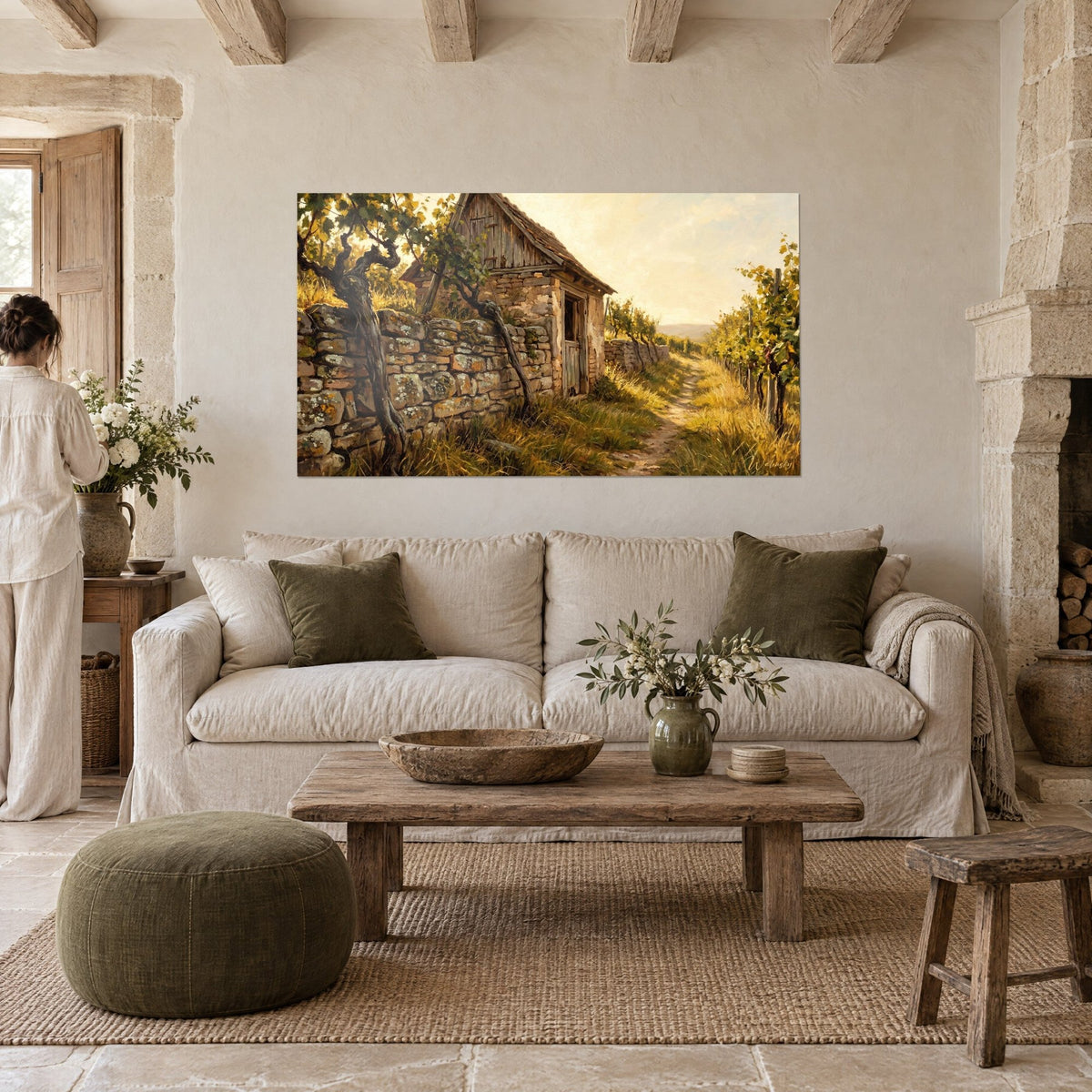 Tableau cabanon de vigneron en pierre ocre, ceps tordus et sentier doré, personne de dos au-dessus d'un canapé dans un salon lumineux