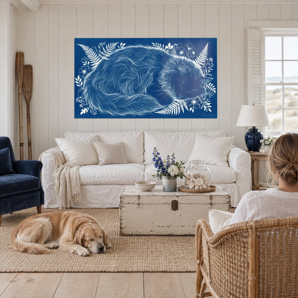 Gemälde einer schlafenden Ragamuffin-Katze im Blau-Weiß-Cyanotypie-Stil, umgeben von Farnen, über einem Sofa in einem hellen Wohnzimmer