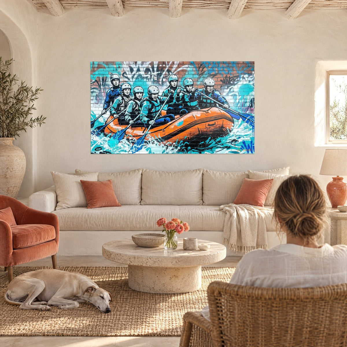 Wall art rafting crew in helmets paddling an orange raft over turquoise water, above a sofa in a bright living room