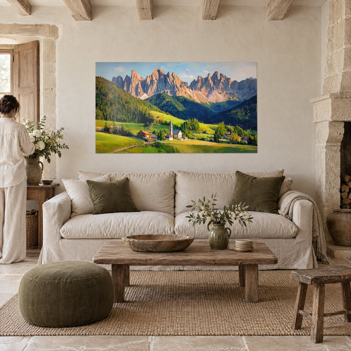Wall art alpine village nestled beneath rosy peaks, soft green meadows, white church steeple, woman seen from behind, above a sofa in a bright living room